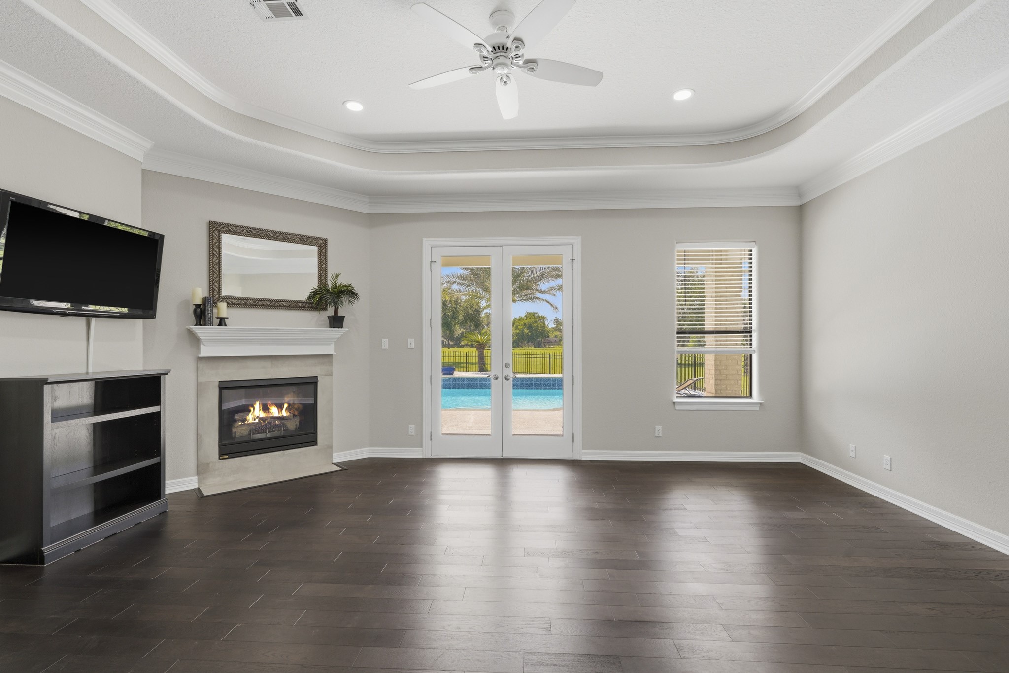 Expansive primary suite with tray ceiling and fireplace