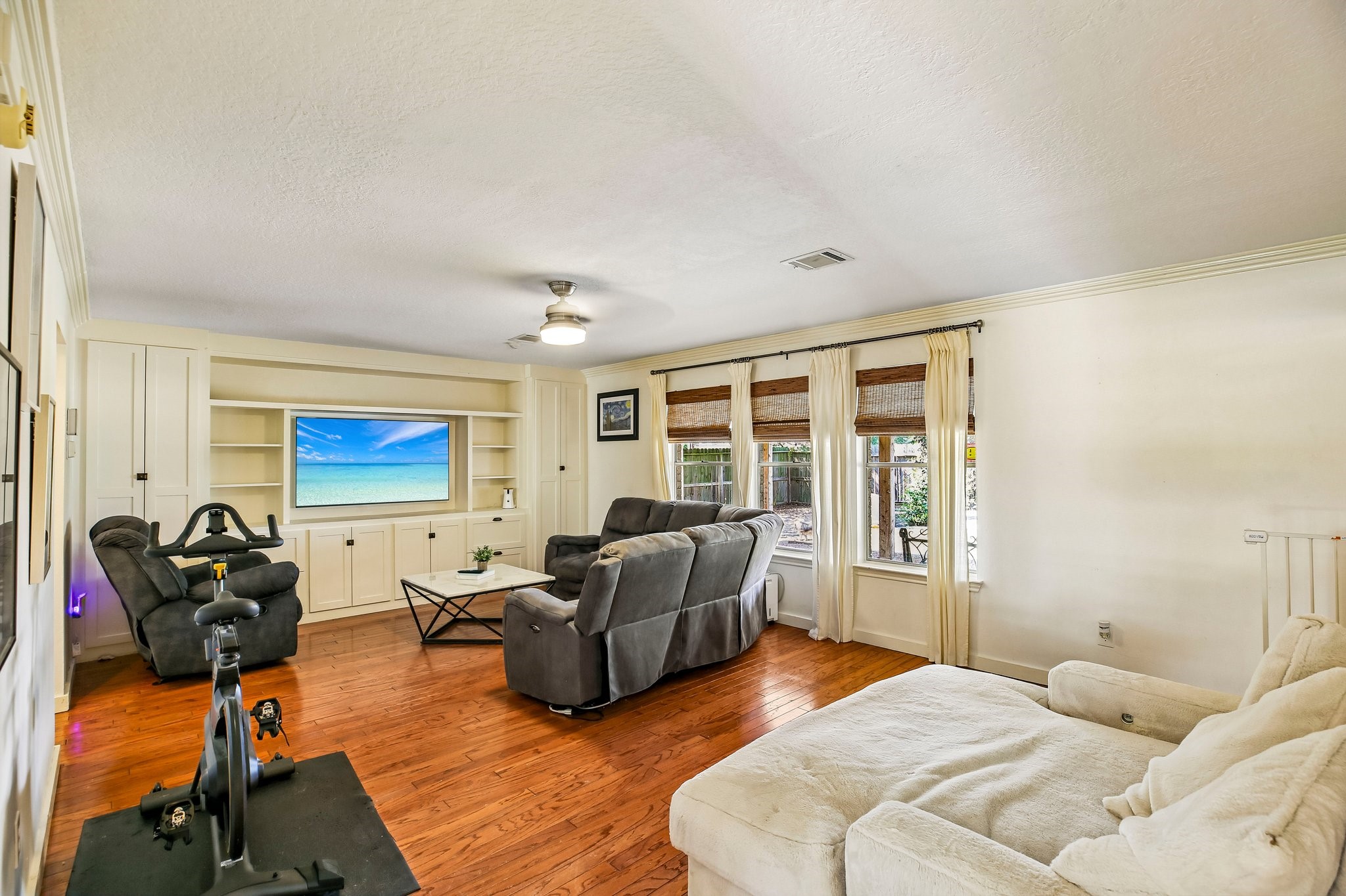 Living room with a wall of beautiful built-ins and hard wood floors.