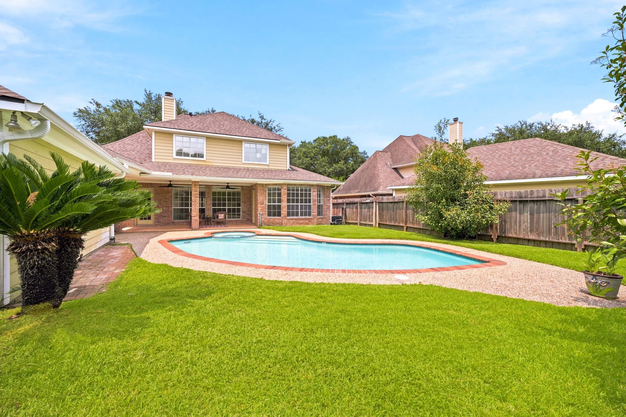Experience a serene backyard oasis featuring a spacious layout with a refreshing pool and relaxing jacuzzi.
