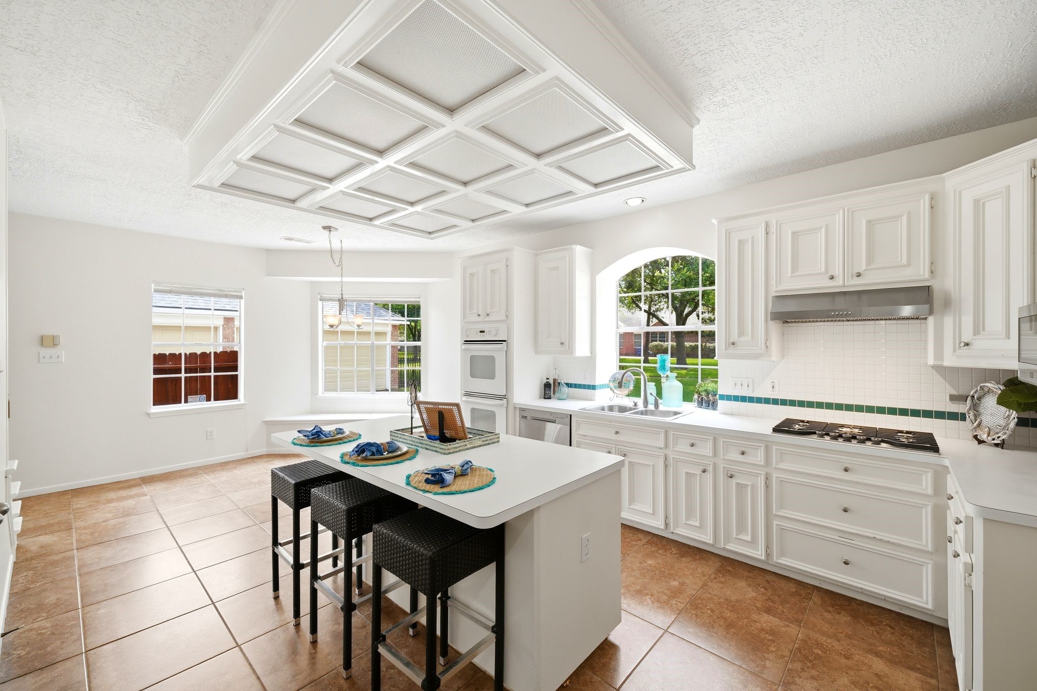 Bright and inviting, this kitchen boasts sleek white appliances, a built-in gas cooktop, and a spacious pantry, perfect for culinary enthusiasts.