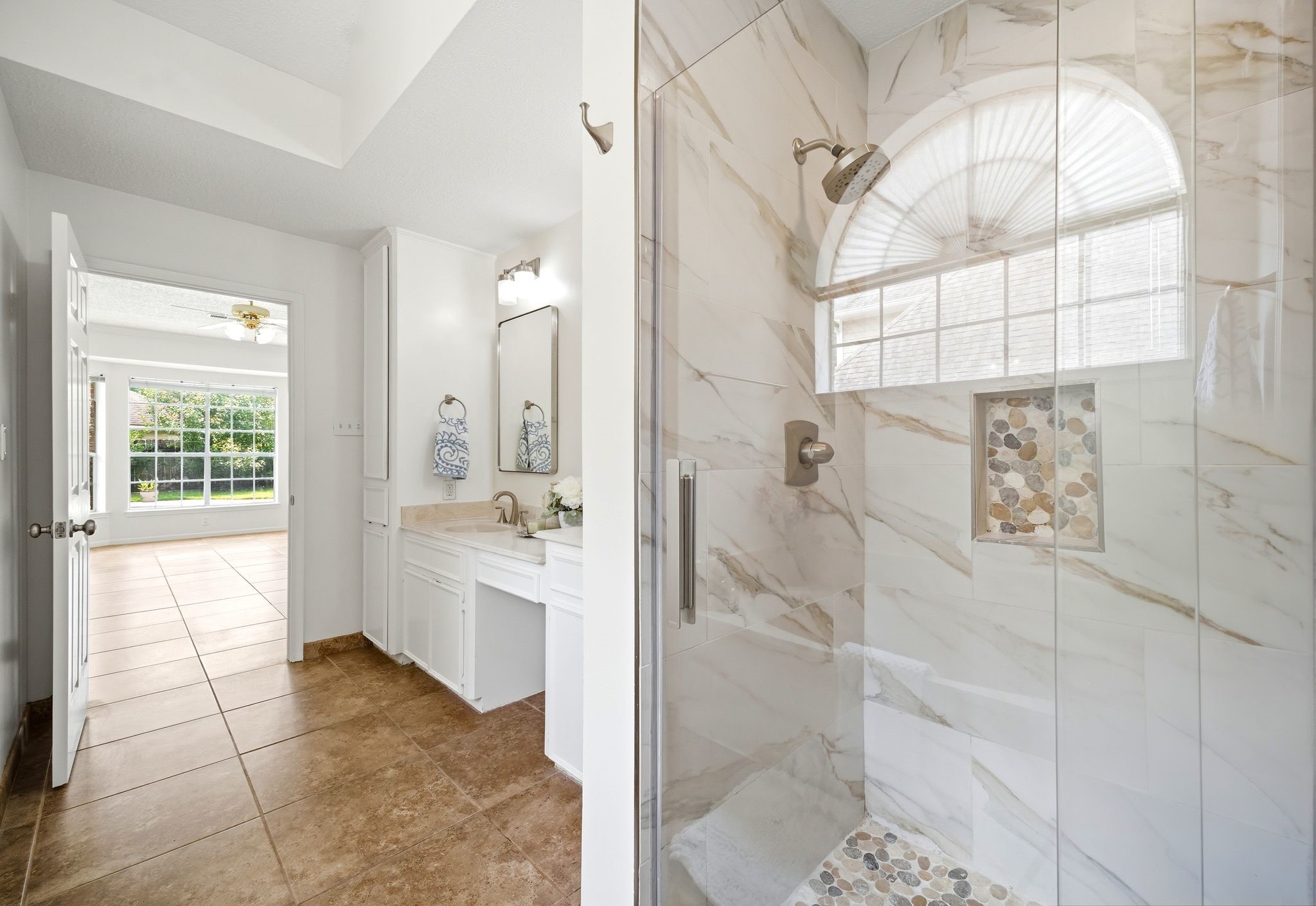 Experience luxury in the elegant walk-in shower featuring pebble-like tile and sleek new glass doors.