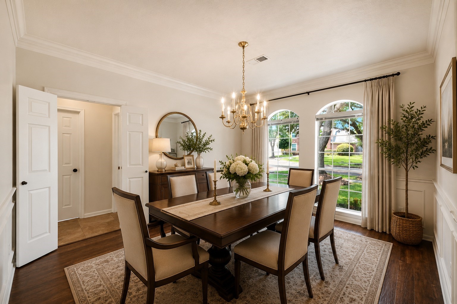 Elegantly brightened by two arched windows with serene outdoor views, this dining room offers seamless access to the kitchen, ideal for effortless entertaining.