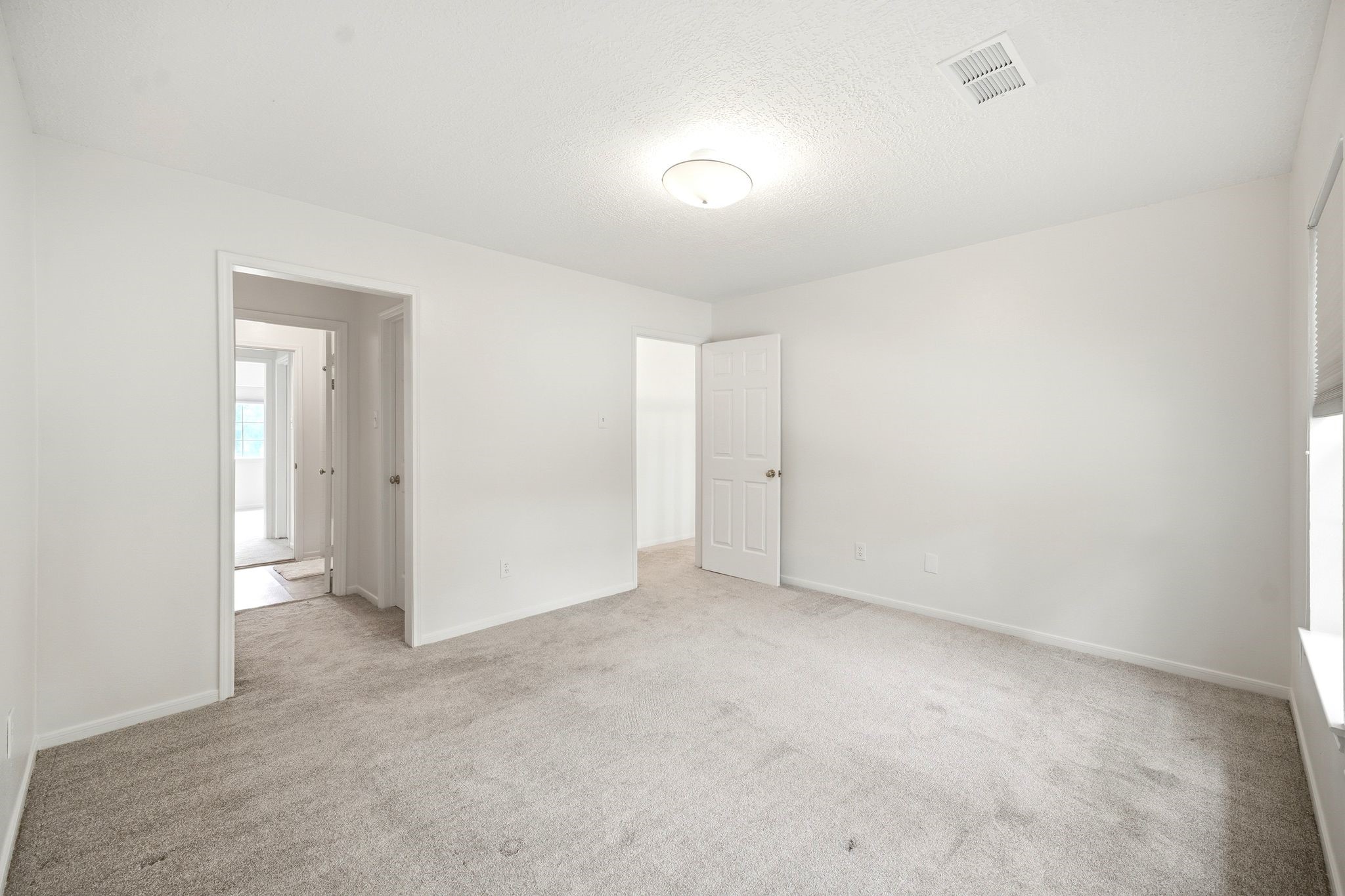 Spacious and bright, this secondary bedroom offers a blank canvas with plush carpeting and ample natural light, perfect for personalizing your ideal retreat.
