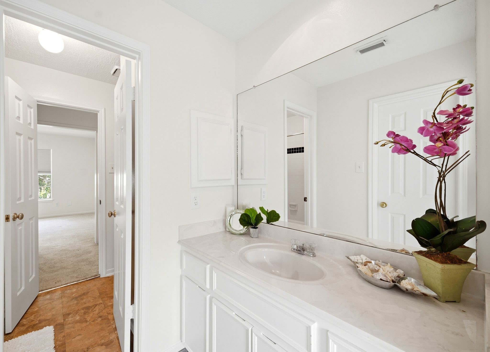 Experience the elegance of a bright bathroom featuring a large mirror and a separate vanity, perfect for a refreshing start to your day.