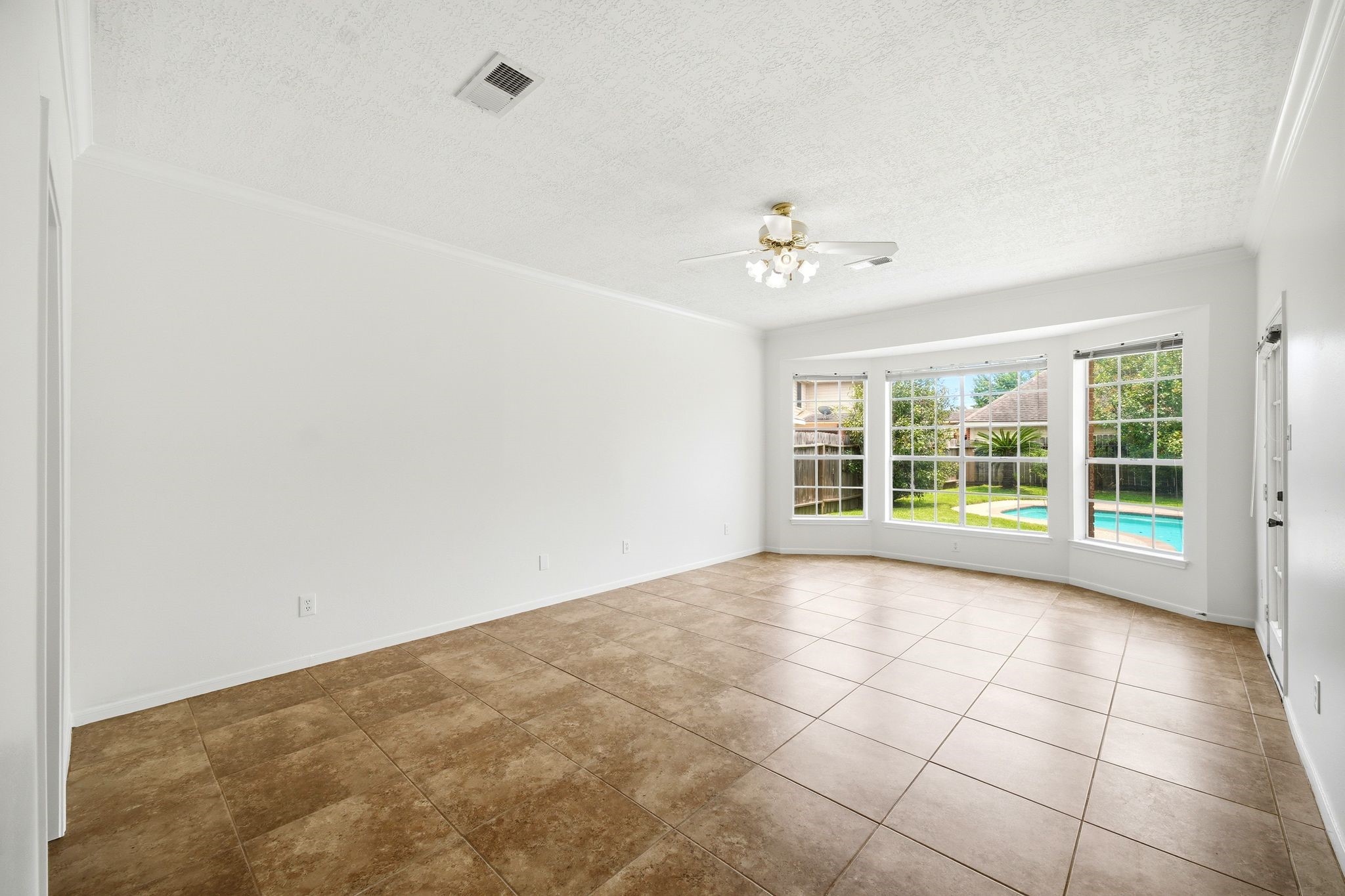 Spacious primary bedroom with abundant natural light, featuring large windows overlooking the pool and a versatile open layout perfect for your personal touch.