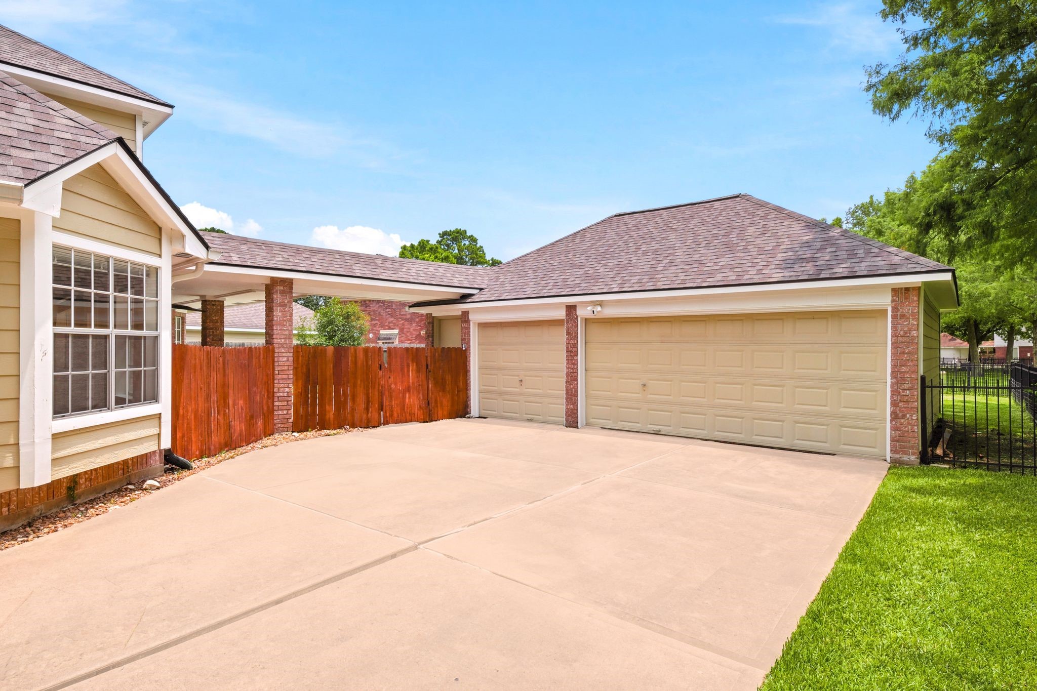 A spacious driveway leads to a two-car garage, bordered by a charming wooden fence that guides you to the inviting pool and expansive backyard.