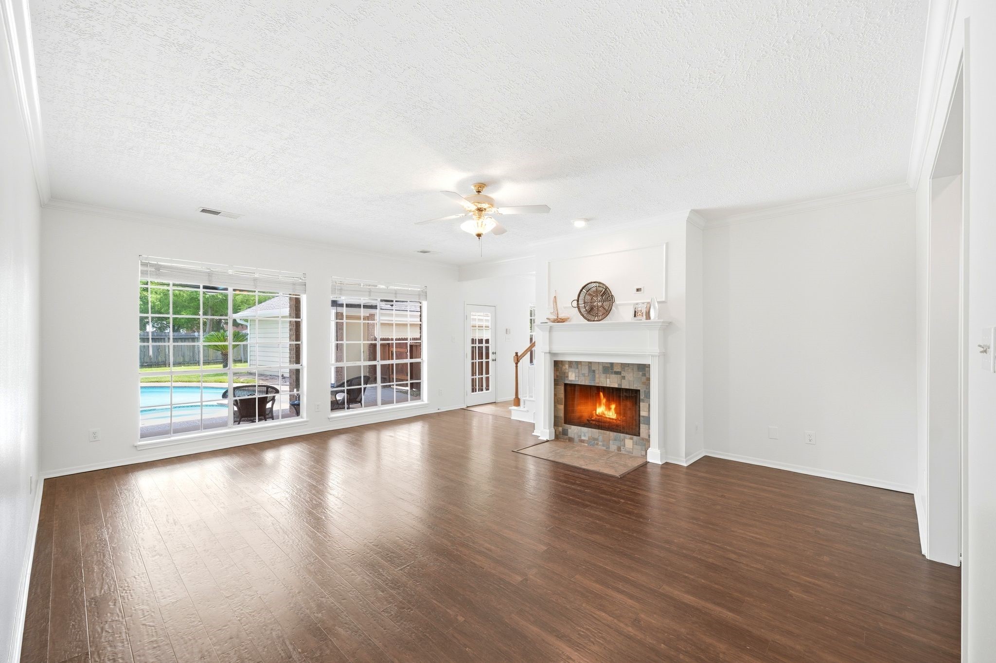 Spacious and bright, this living room features elegant floors, a cozy fireplace, and large windows offering serene views of the pool, perfect for creating your dream space.
