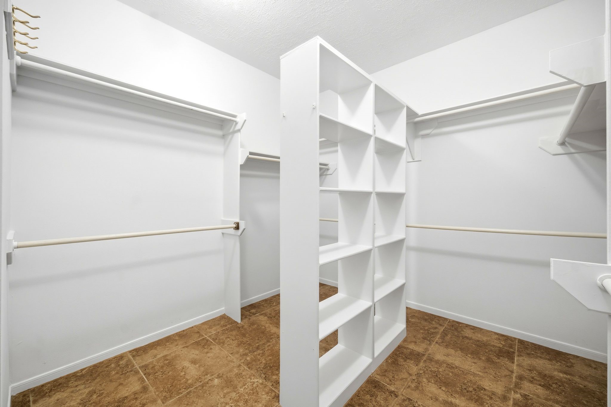 Discover the ultimate in organization with this spacious walk-in closet, boasting ample shelving, hanging rods, and a central divider for perfectly arranged storage.