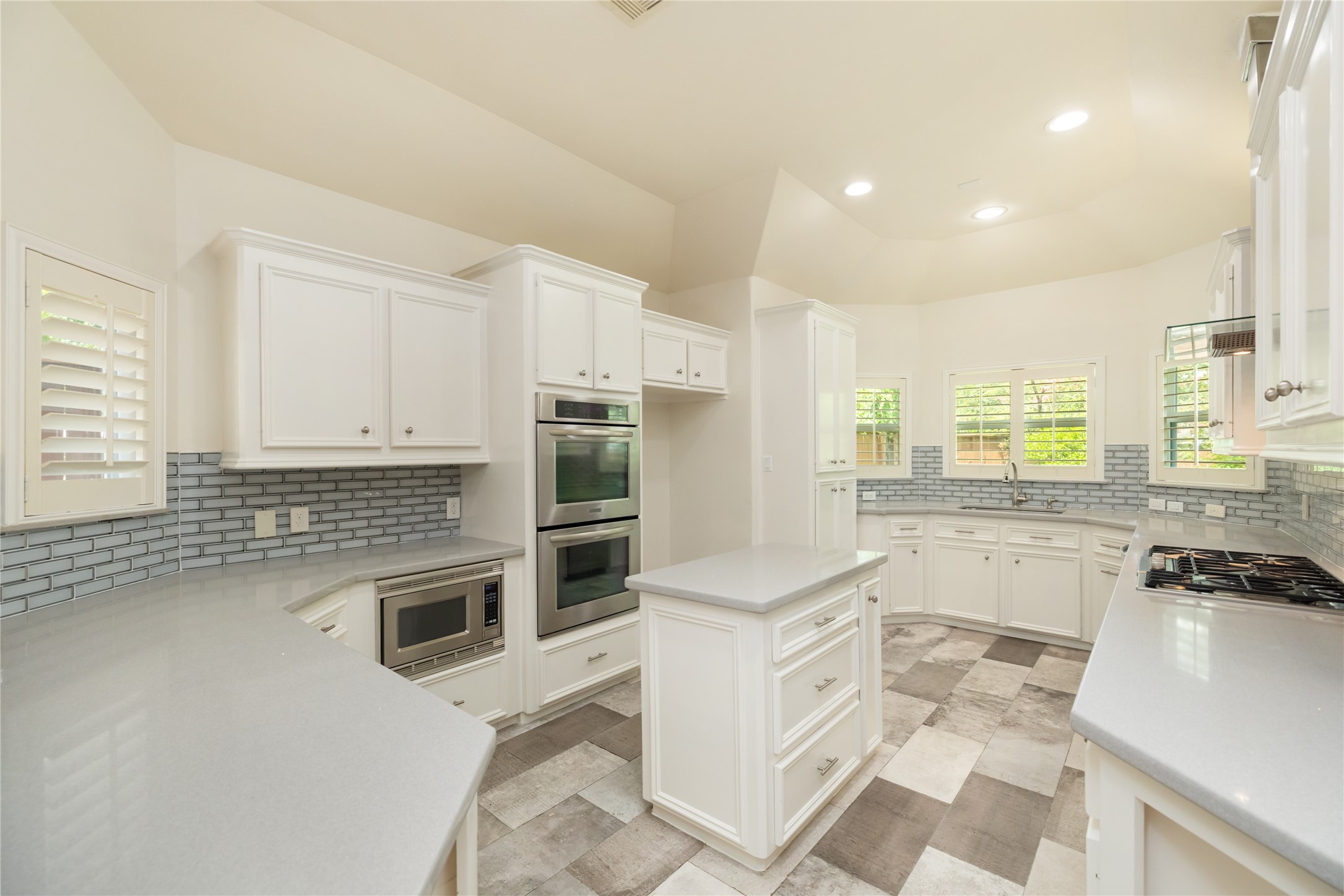 Light and bright kitchen with Silestone countertops, under cabinet lighting, farmhouse sink, gas range, double ovens, built in microwave and more!