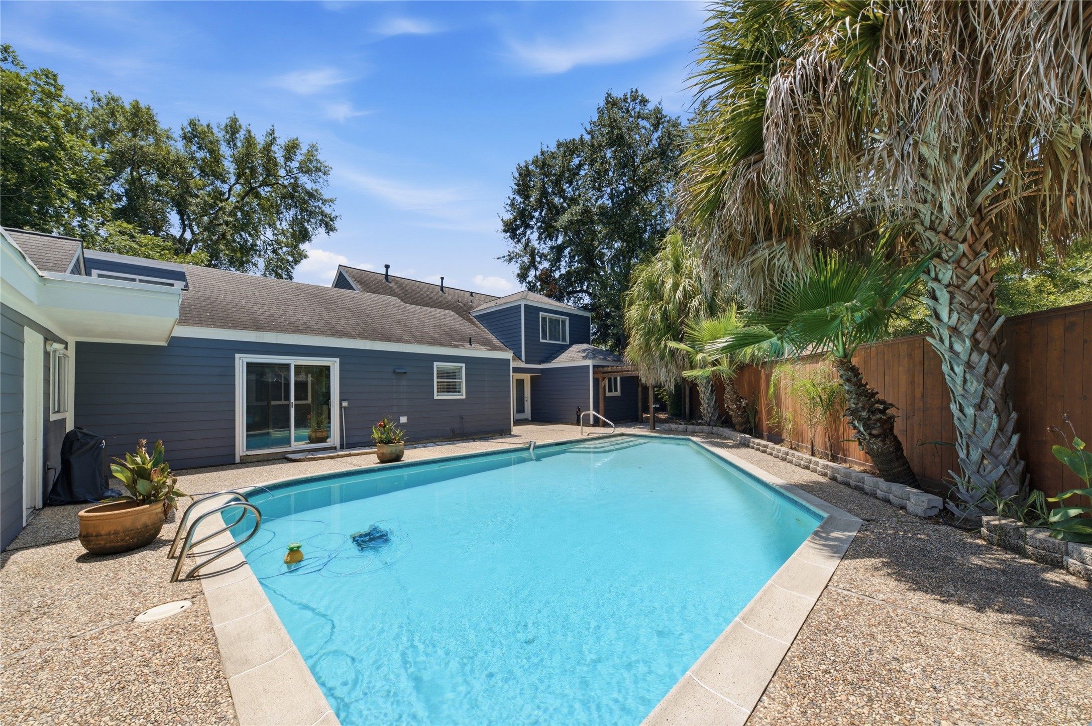 Tropical paradise in your own backyard, complete with lush palms and a sun-drenched pool deck.