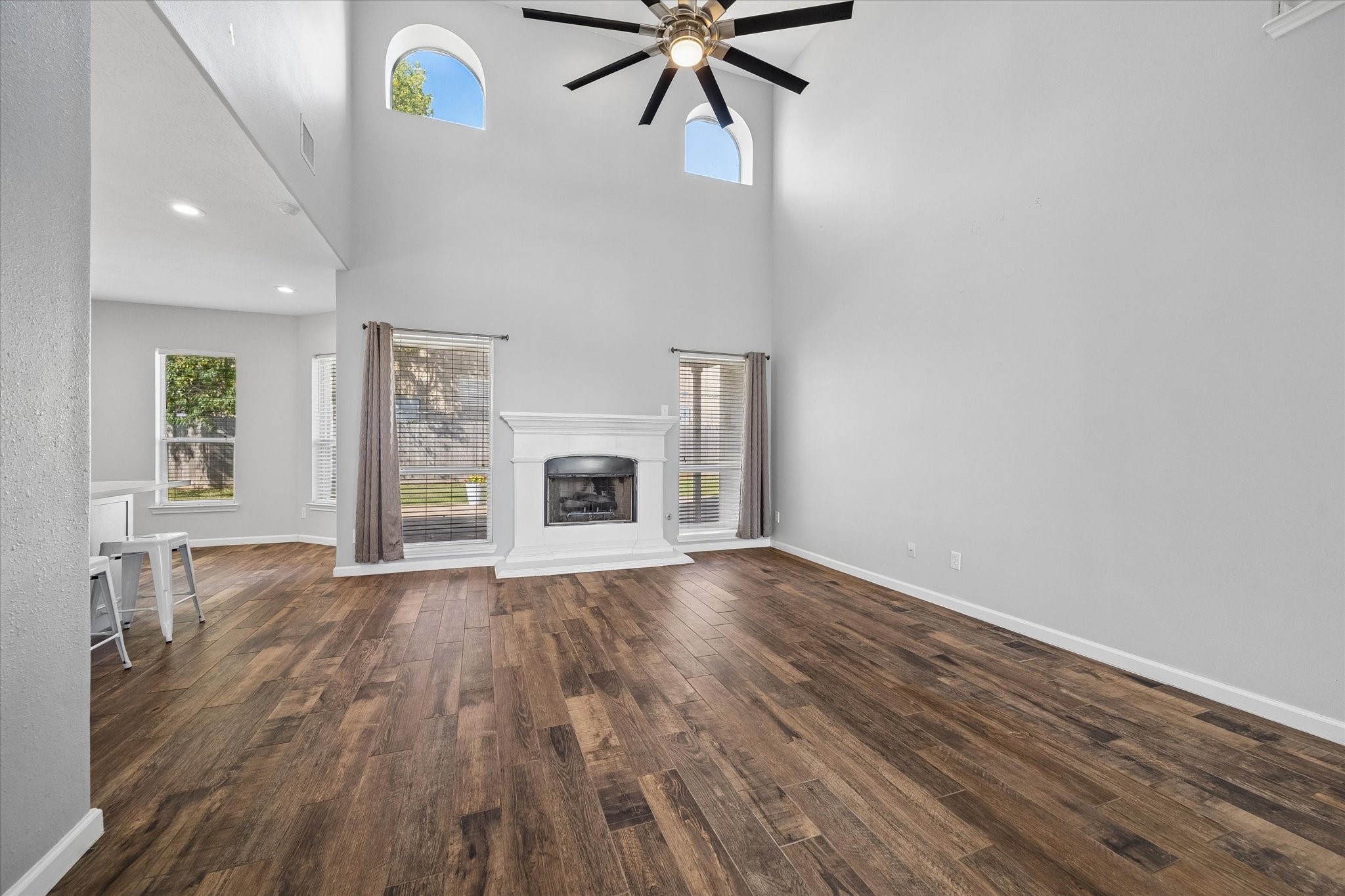 Two-story HIGH CEILINGS and double arched windows let sunlight stream into the living room.  A gorgeous gas-log fireplace anchors the room.