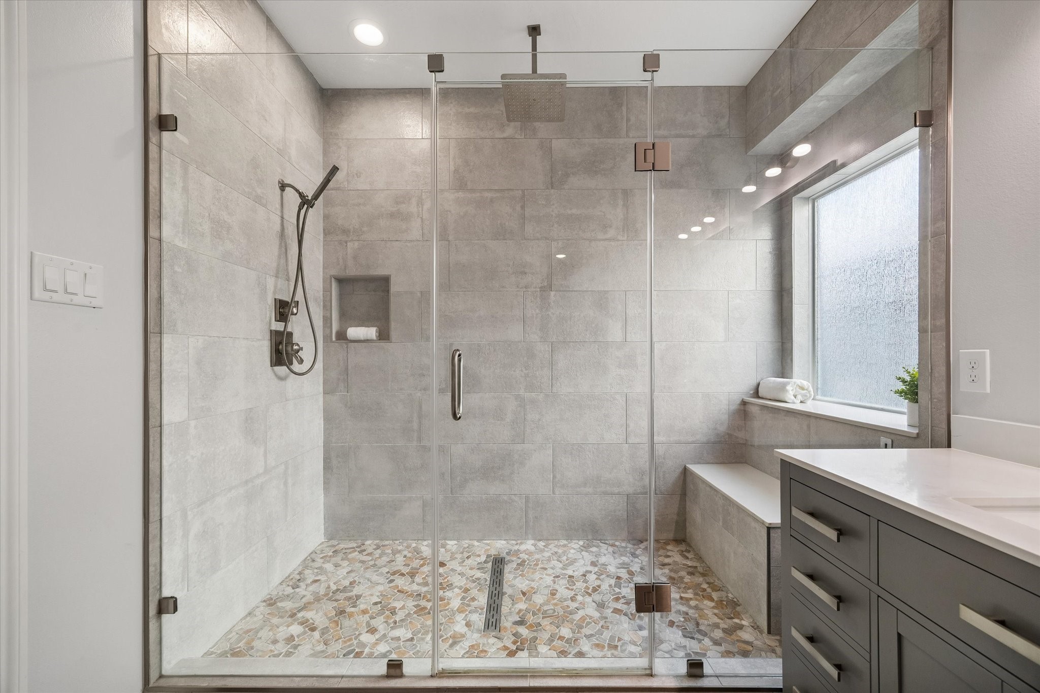 This amazing HUGE walk-in shower features beautiful tile work, shower wand AND rainhead, wall niche, built-in bench, and a window with privacy glass.