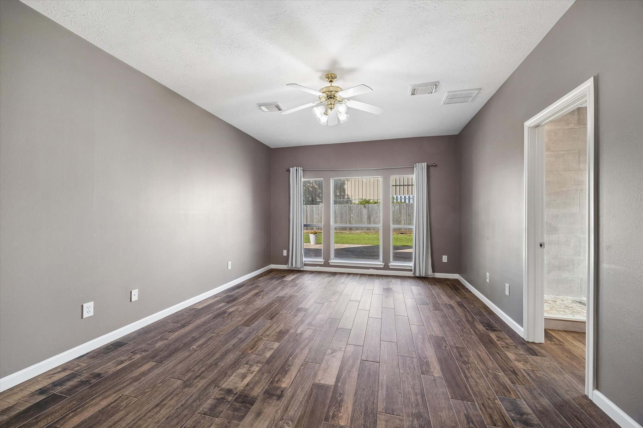 The spacious primary suite is tucked away at the rear of the home on the first floor. Wide windows let sunshine in and provide a view of the backyard. No carpet!