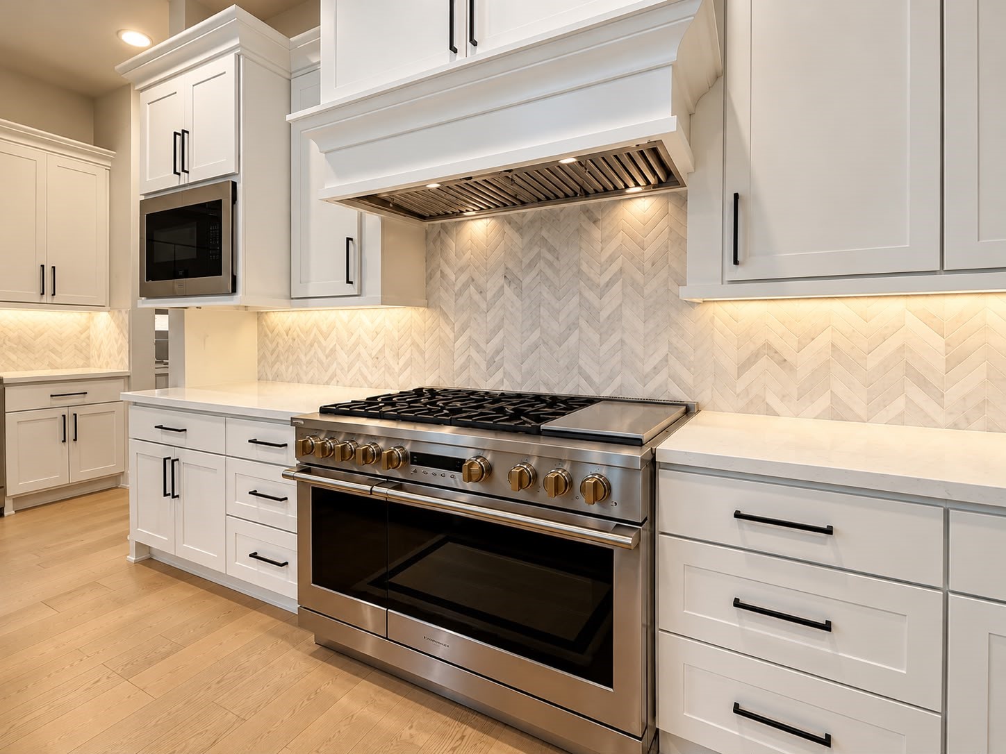 Modern gourmet kitchen featuring white shaker cabinets, stainless steel professional-style gas range, custom range hood, herringbone tile backsplash, and elegant countertops.