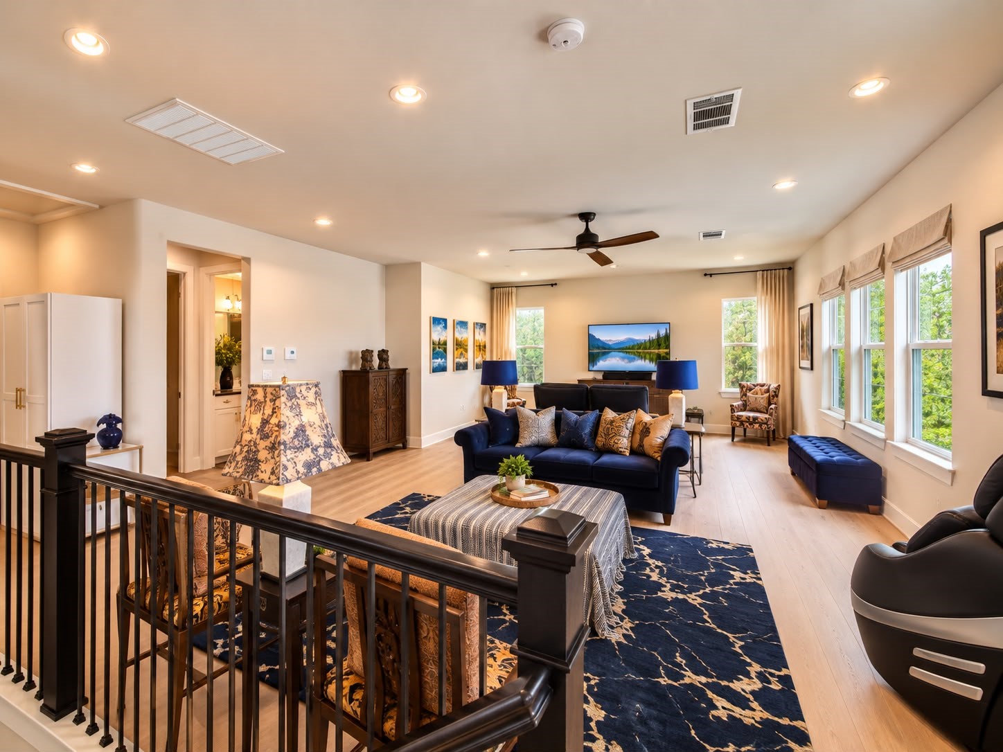 Bright and spacious living area with large windows, stylish blue seating, elegant accent furnishings, and an open layout ideal for entertaining.