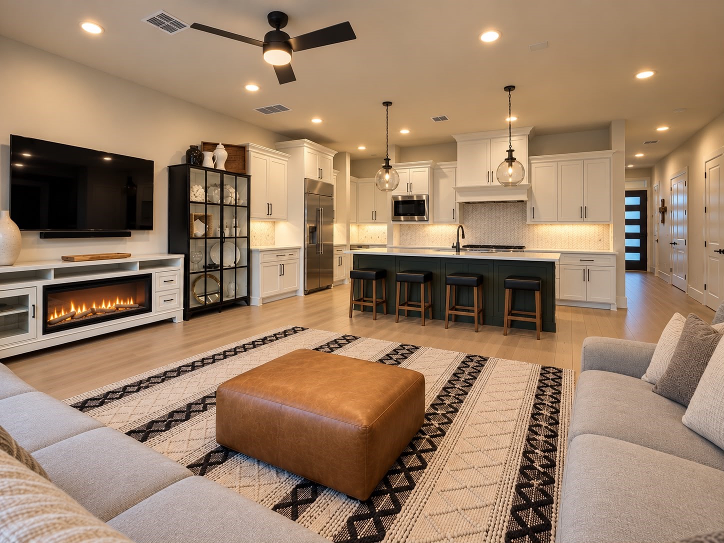 Spacious open-concept living area with a cozy fireplace, contemporary furnishings, a stylish kitchen island, and elegant pendant lighting.