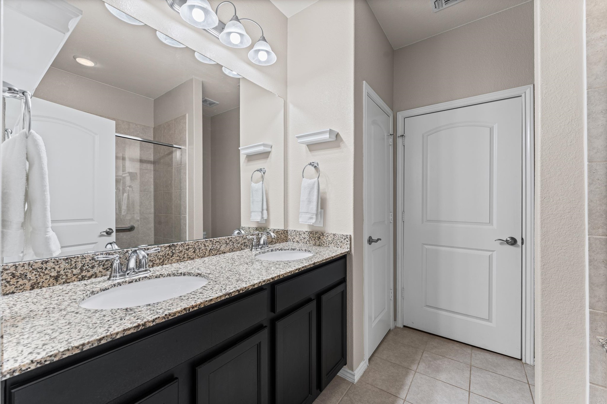 A commodious double vanity setup combined with generous cabinet storage and an integrated linen closet offers the ultimate blend of luxury and practical layout design