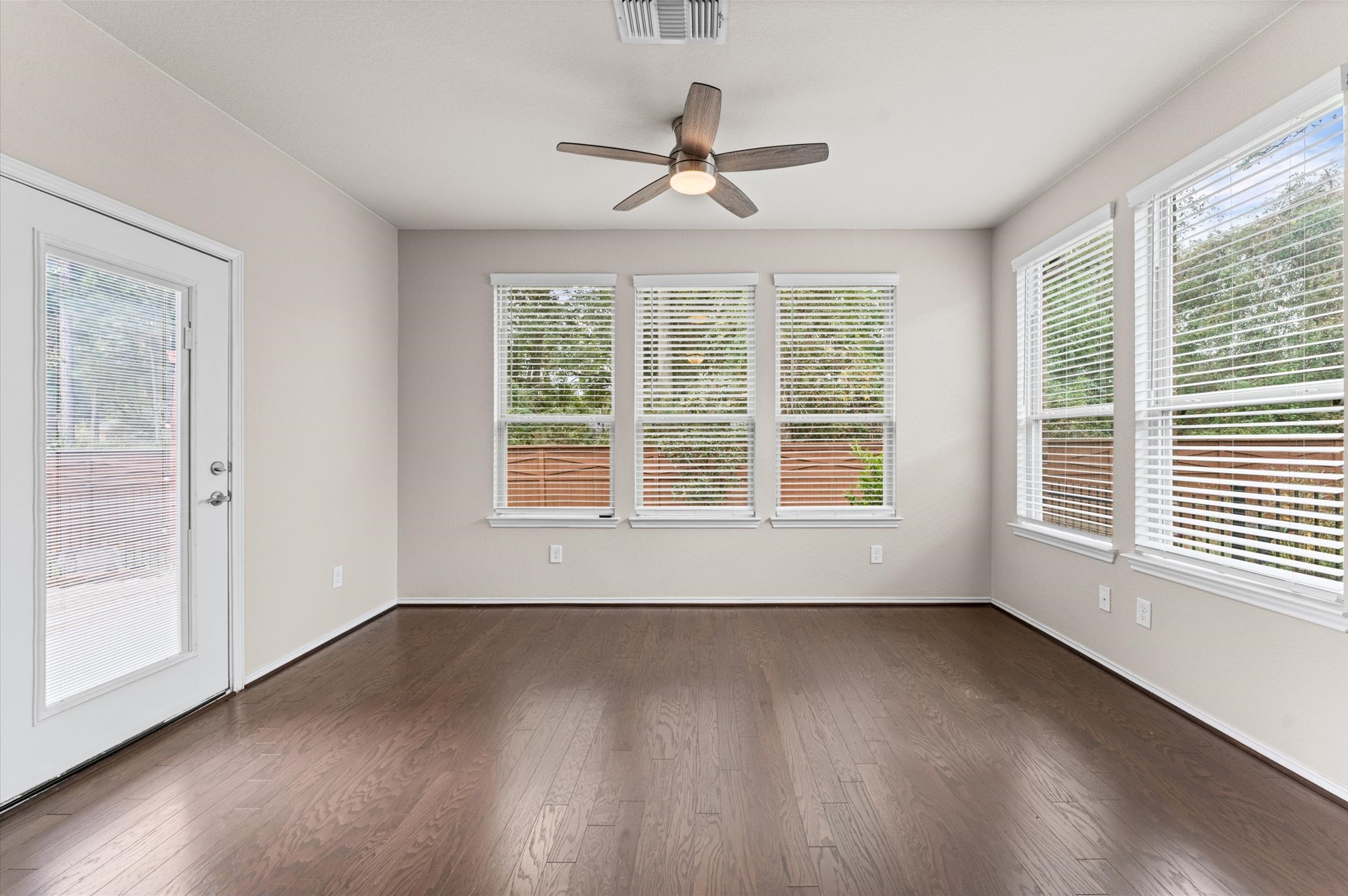 Spilling outward from the central living area, the sunroom boasts large windows that frame sweeping, unobstructed sightlines of the protected, mature green space behind the property.