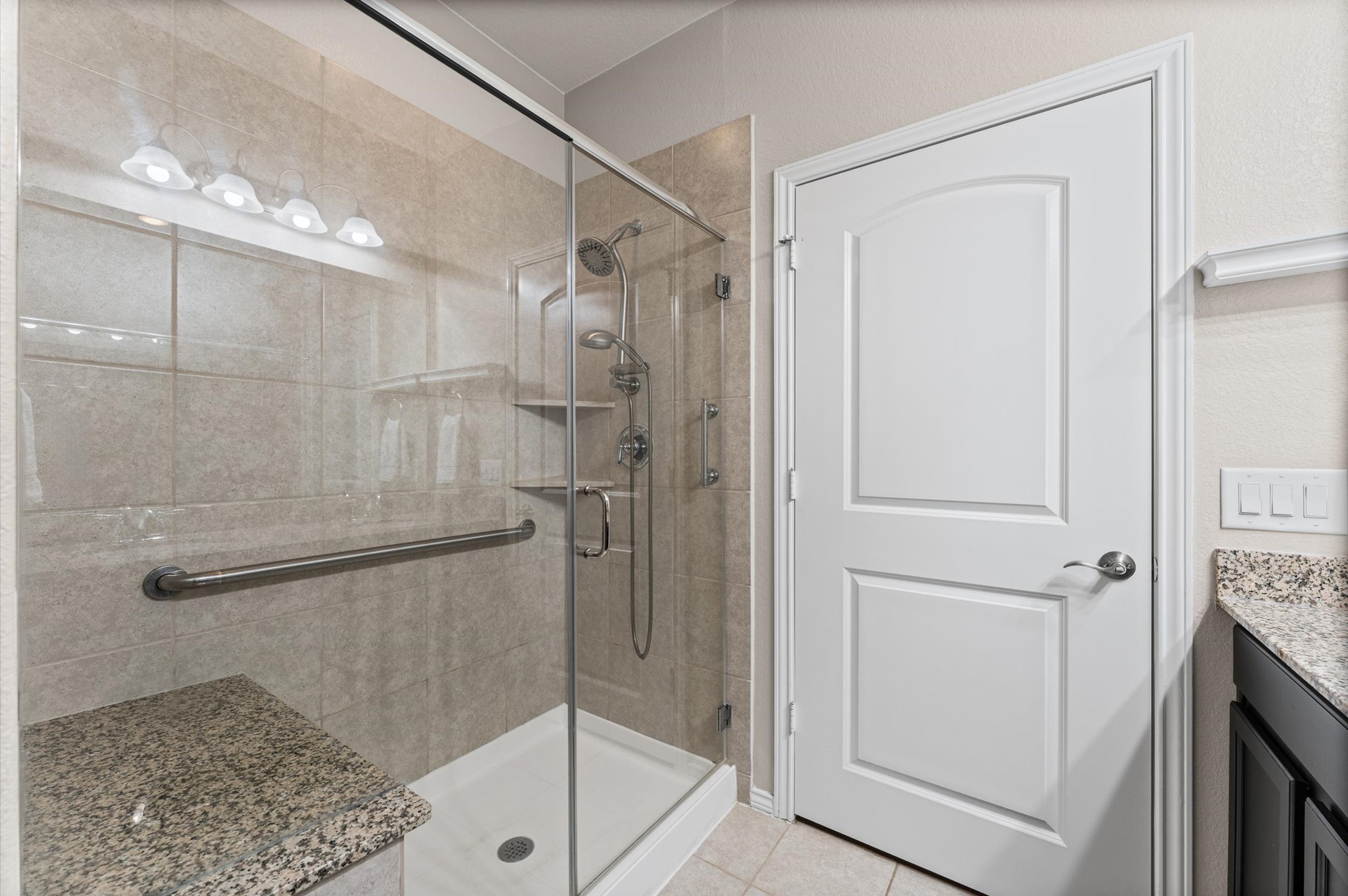 Integrating a double shower head setup, seating, and crucial universal accessibility features like a grab bar within a sleek, modern aesthetic creates a high-performance, spa-like sanctuary.