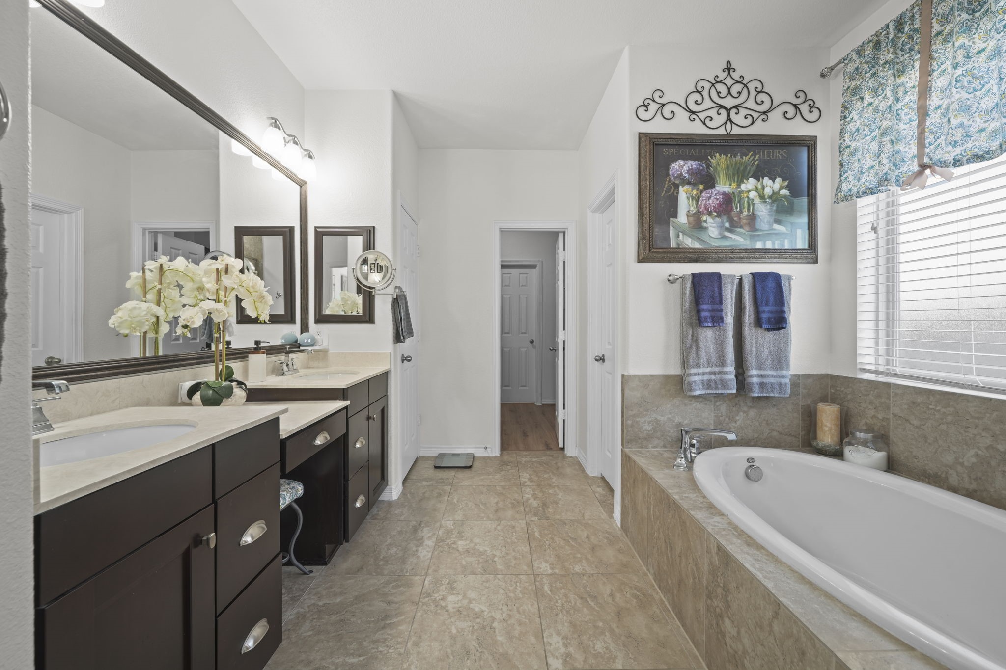 Spacious bathroom featuring a luxurious soaking tub, dual sinks with elegant dark wood cabinetry, and ample natural light.