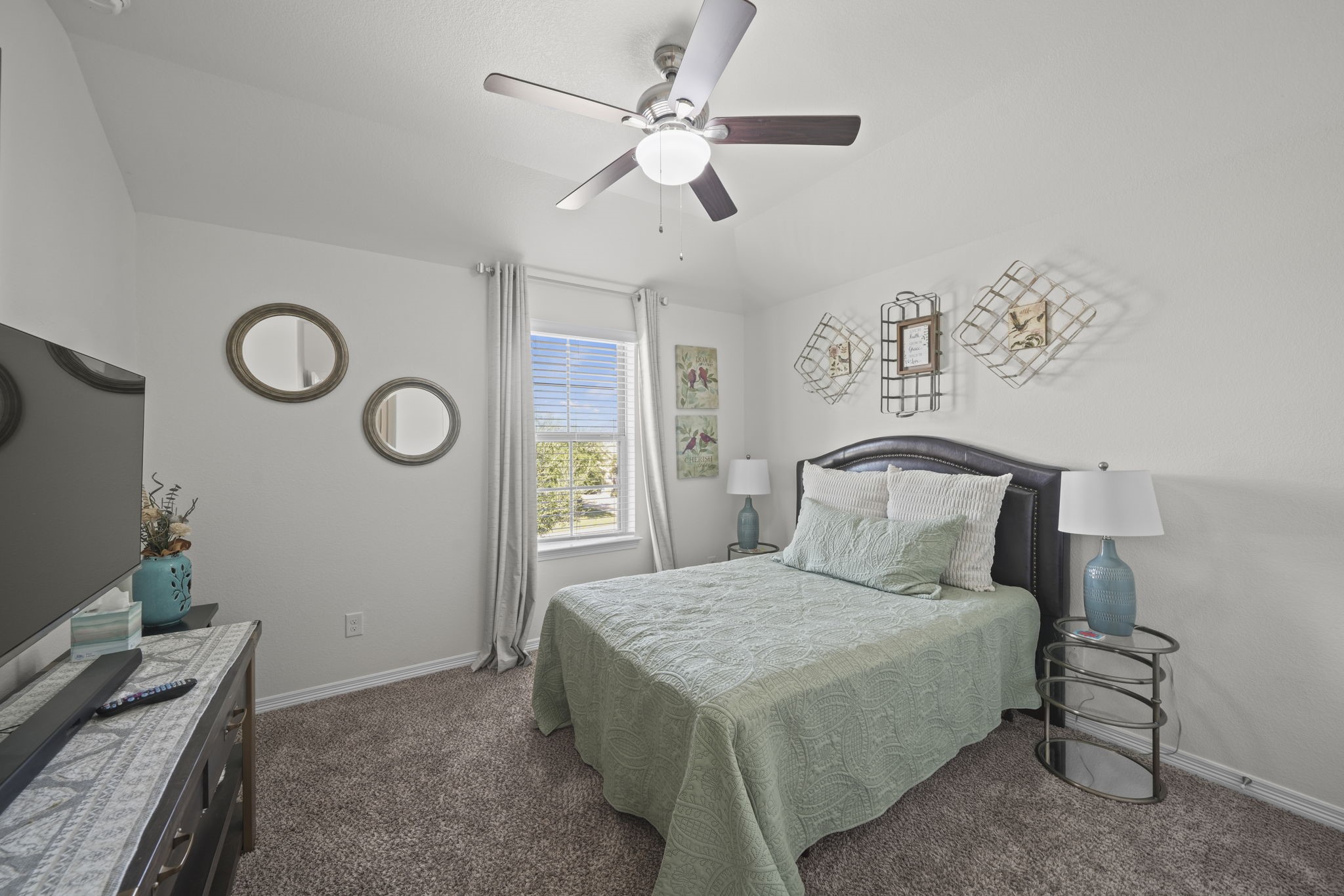 Cozy bedroom featuring a comfortable bed, elegant decor, and a large window allowing natural light to brighten the space.