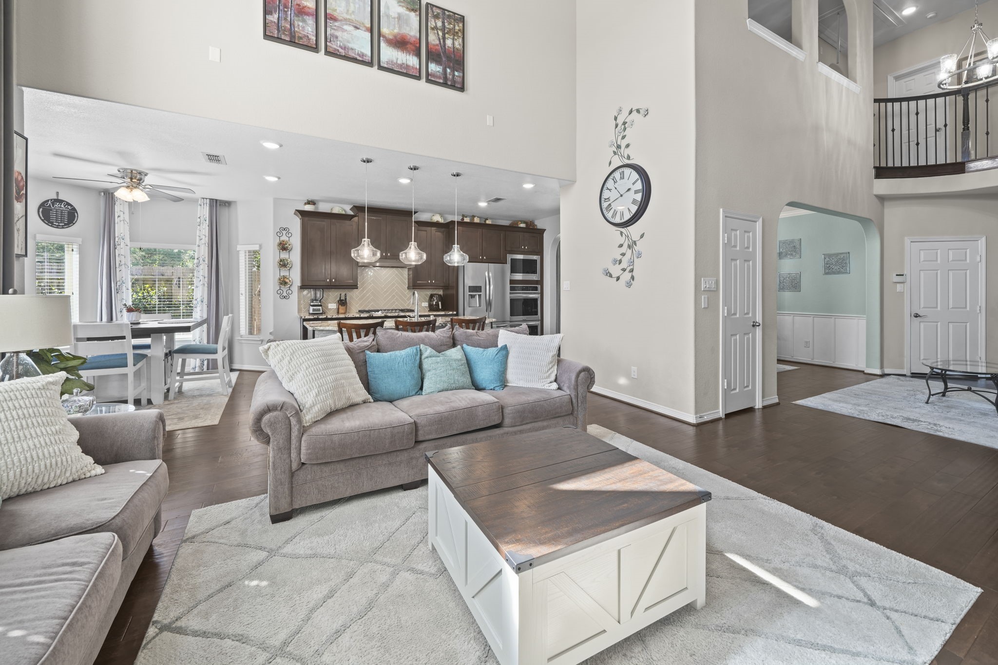 Spacious open-concept living area with high ceilings, elegant lighting, and a seamless flow from the cozy sitting space to the modern kitchen and dining nook.