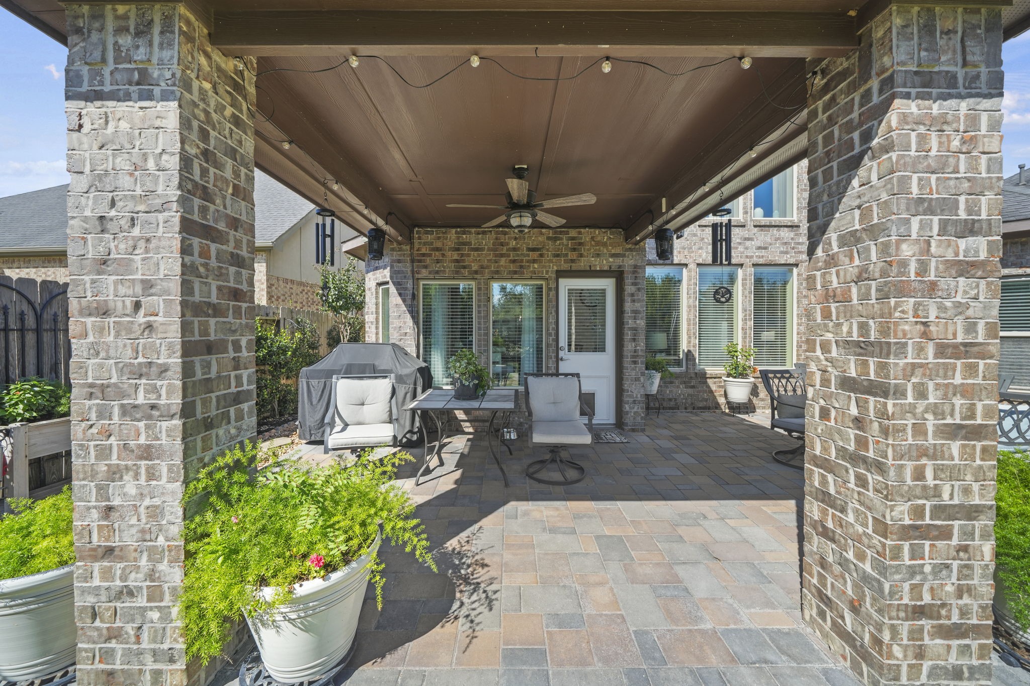 Charming covered patio with brick accents and ample seating, perfect for outdoor entertaining.