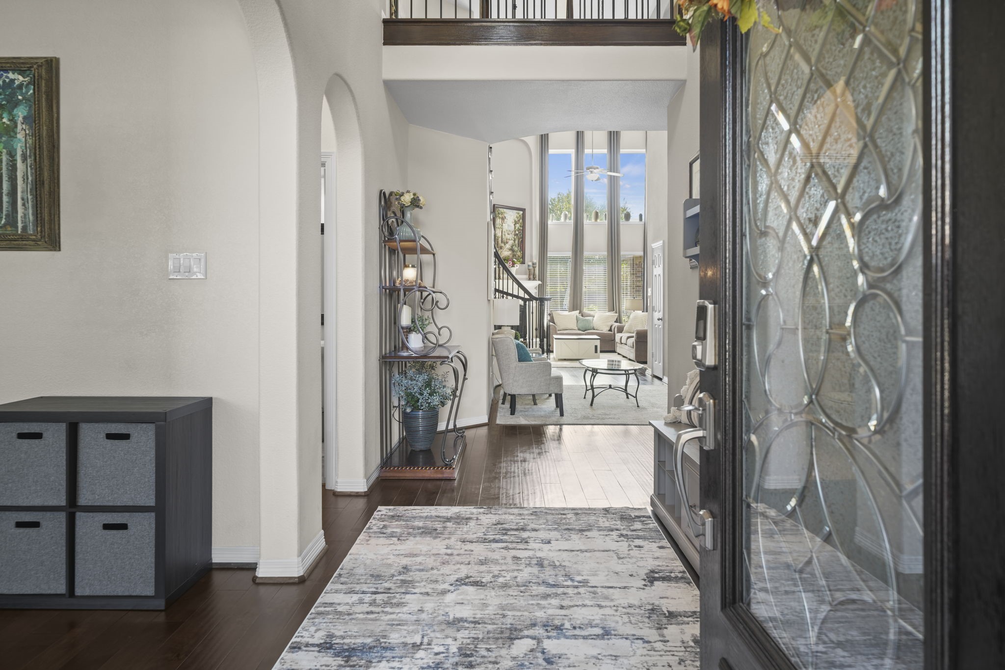 Step into an inviting entryway with elegant hardwood floors leading to a spacious living area. Soaring ceilings and abundant natural light create a bright, open atmosphere perfect for relaxing or entertaining.
