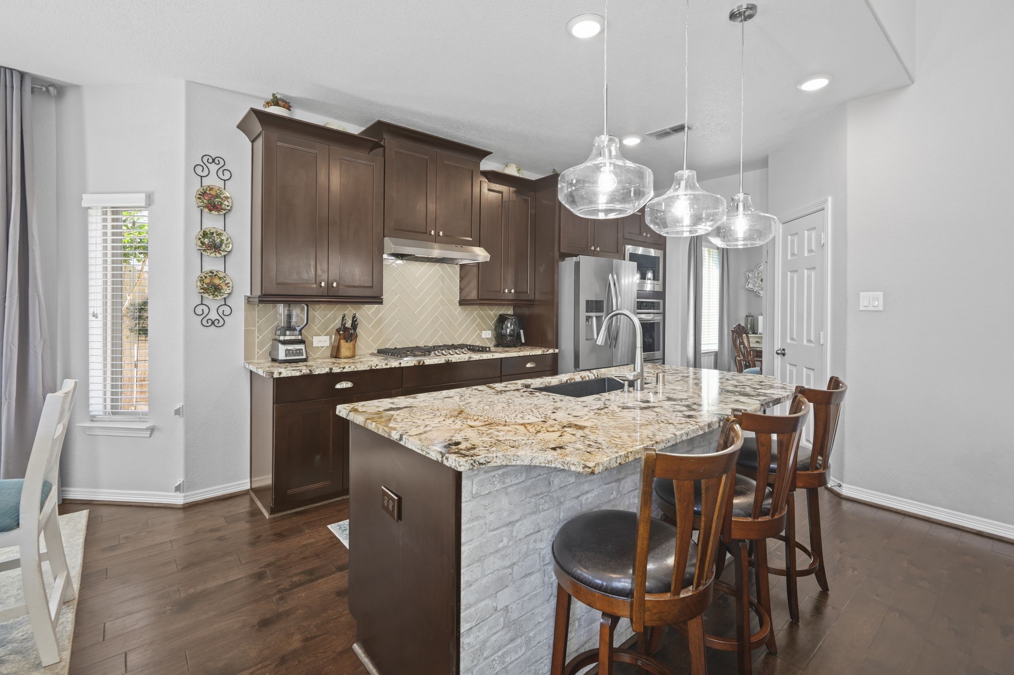 Elegant kitchen featuring rich wood cabinets, a stunning granite island with seating, and modern stainless steel appliances.