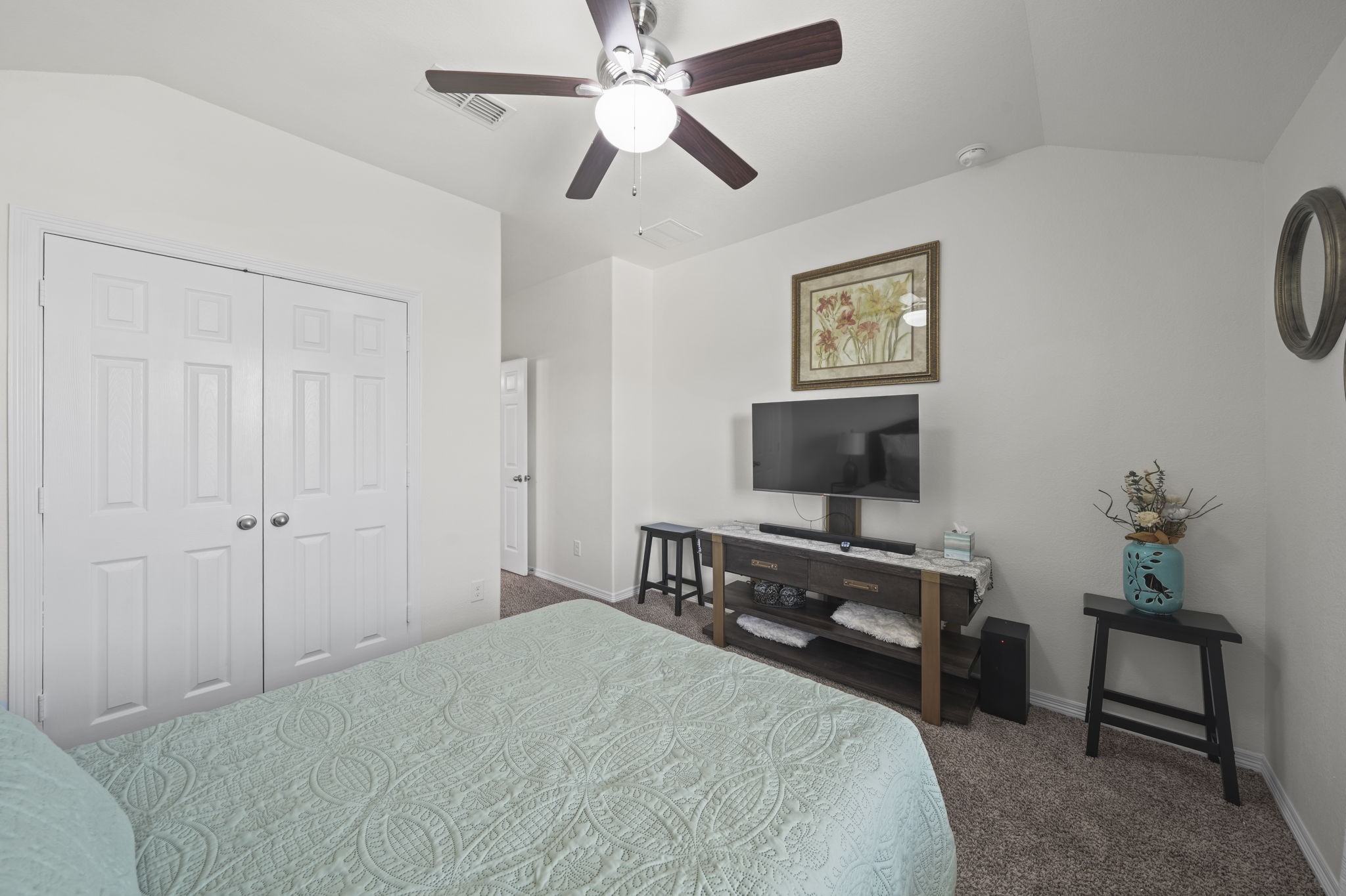 Cozy bedroom featuring a ceiling fan, dual closets, and a mounted TV for relaxed viewing.