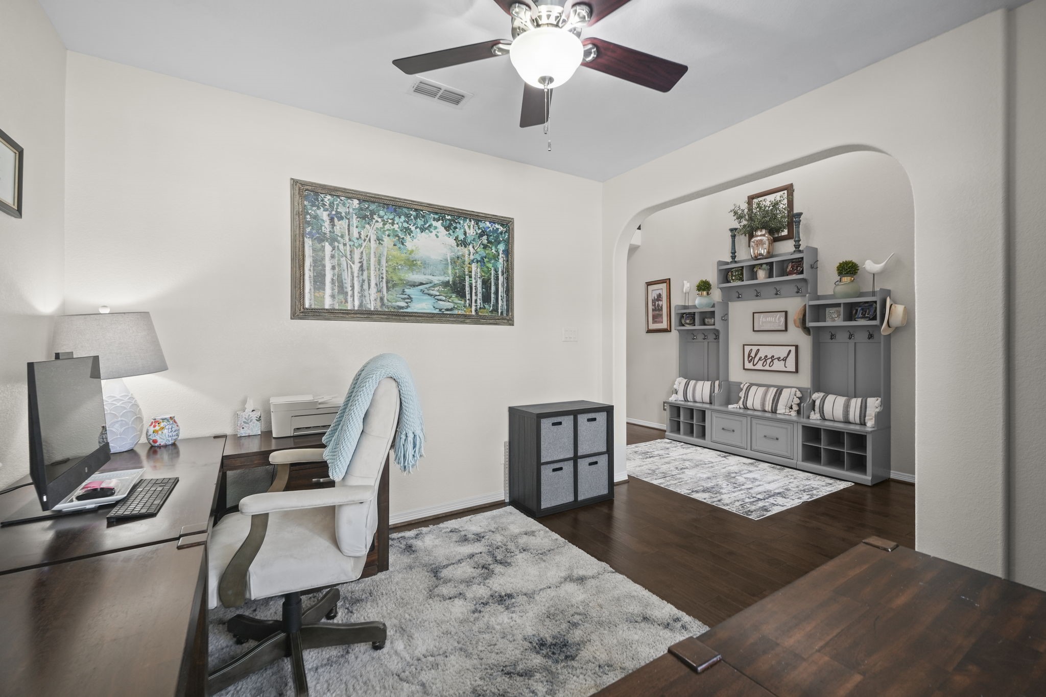 Elegant home office with warm wooden flooring, a cozy workspace, and stylish built-in shelving perfect for organization.