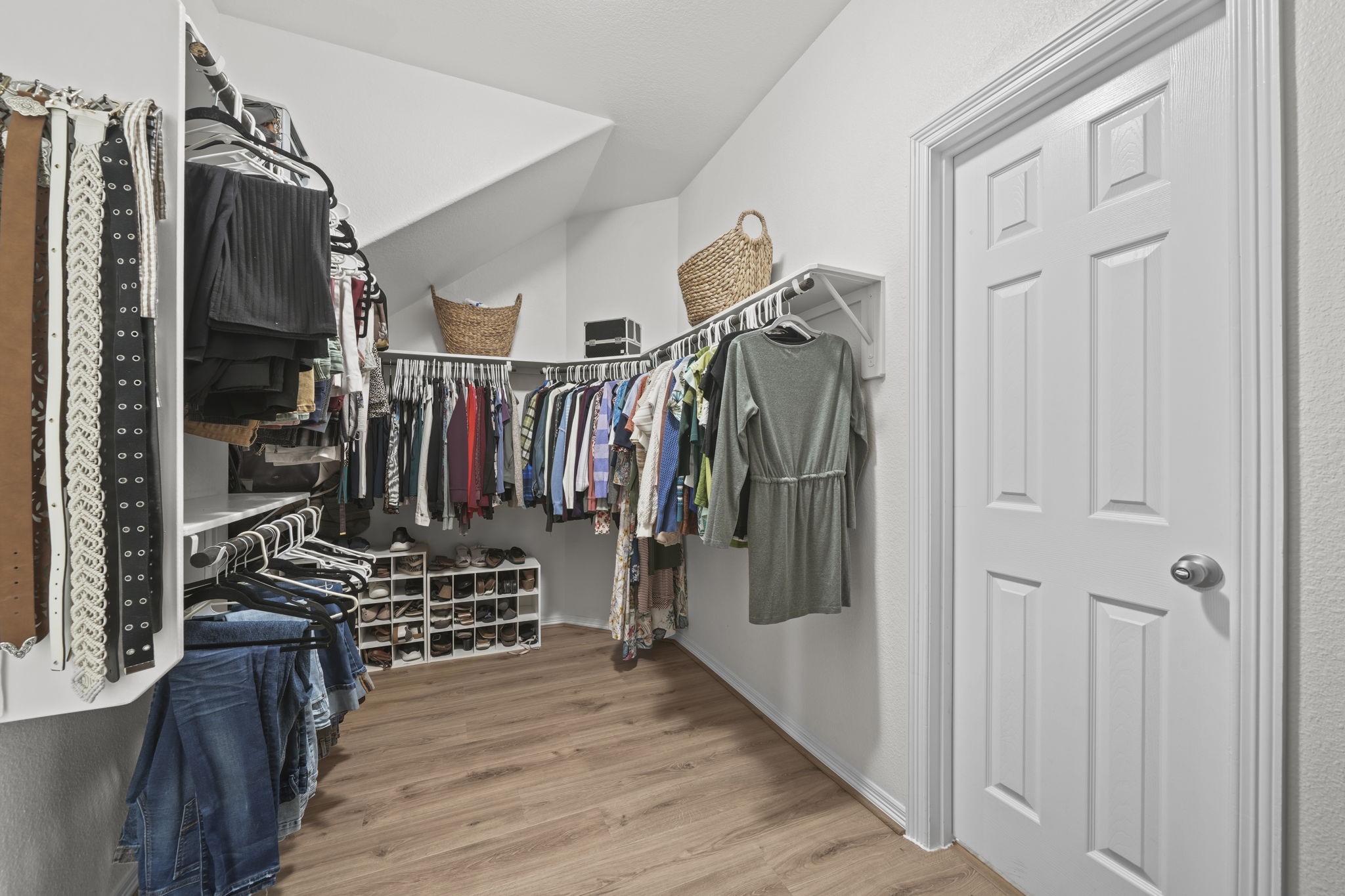 Spacious walk-in closet with ample hanging space, shelving, and shoe storage, featuring a sleek, organized layout with hardwood floors.