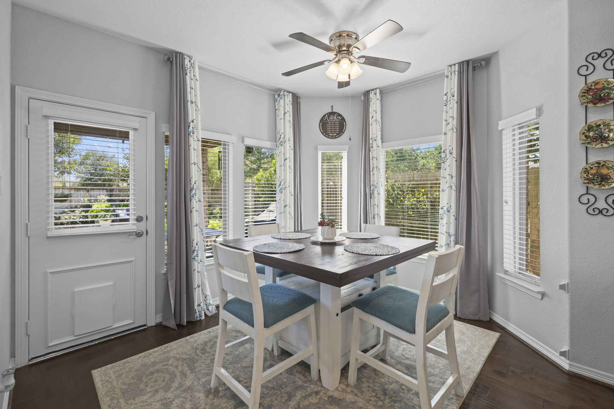 Bright and inviting breakfast nook with abundant natural light, featuring large windows, a stylish ceiling fan, and a cozy dining area perfect for morning gatherings.