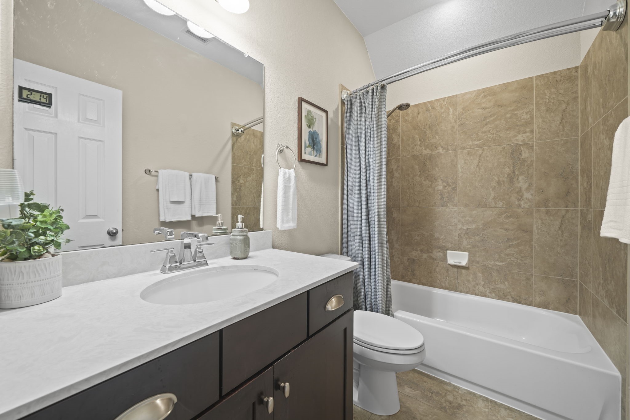 Charming bathroom with elegant tilework, a sleek vanity, and a relaxing bathtub, complemented by modern fixtures and ample lighting.