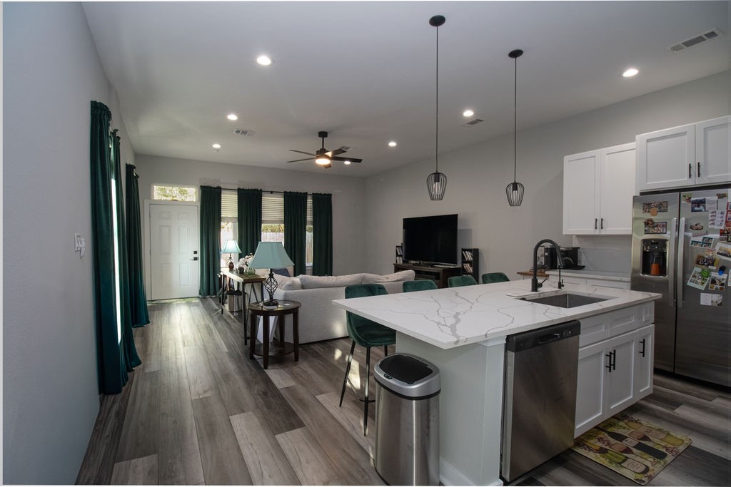 Beautifully designed kitchen featuring white shaker-style cabinetry, stainless steel appliances, attractive countertops, stylish pendant lighting, and an oversized island with seating for four. A wonderful space for gathering and entertaining!