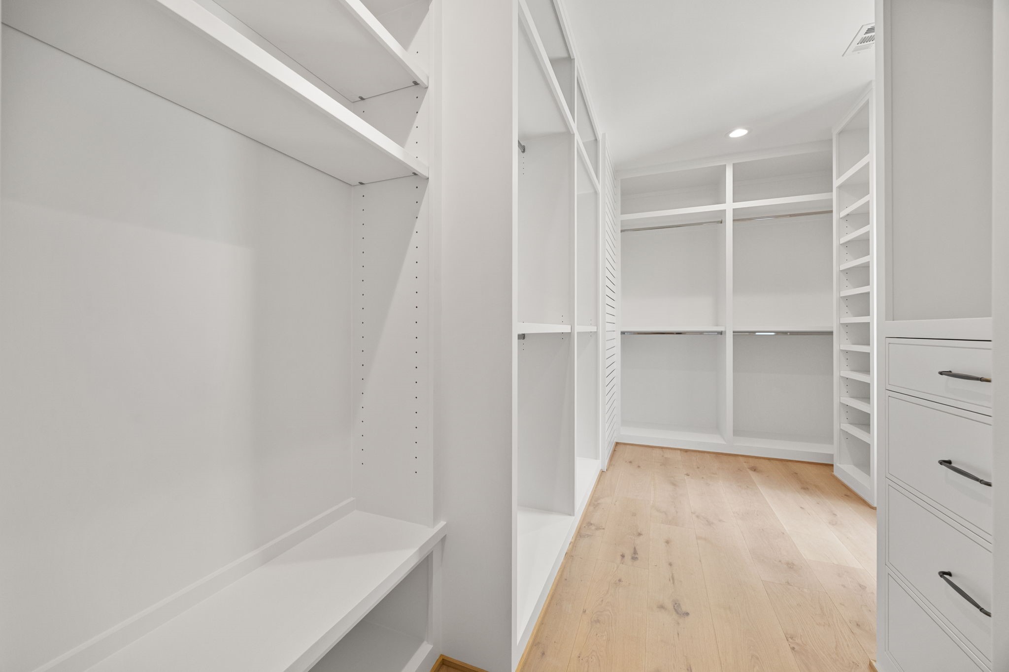 The upstairs primary closet offers abundant custom shelving and cabinetry, providing exceptional organization and storage.