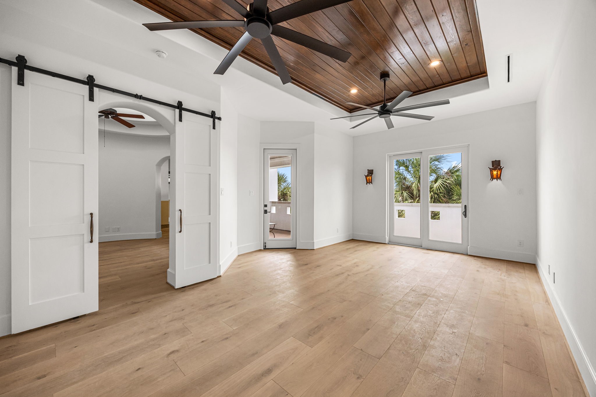 Upstairs, the primary suite is enhanced by a rich wood ceiling and two sets of doors that open to a balcony showcasing serene resort-style views.