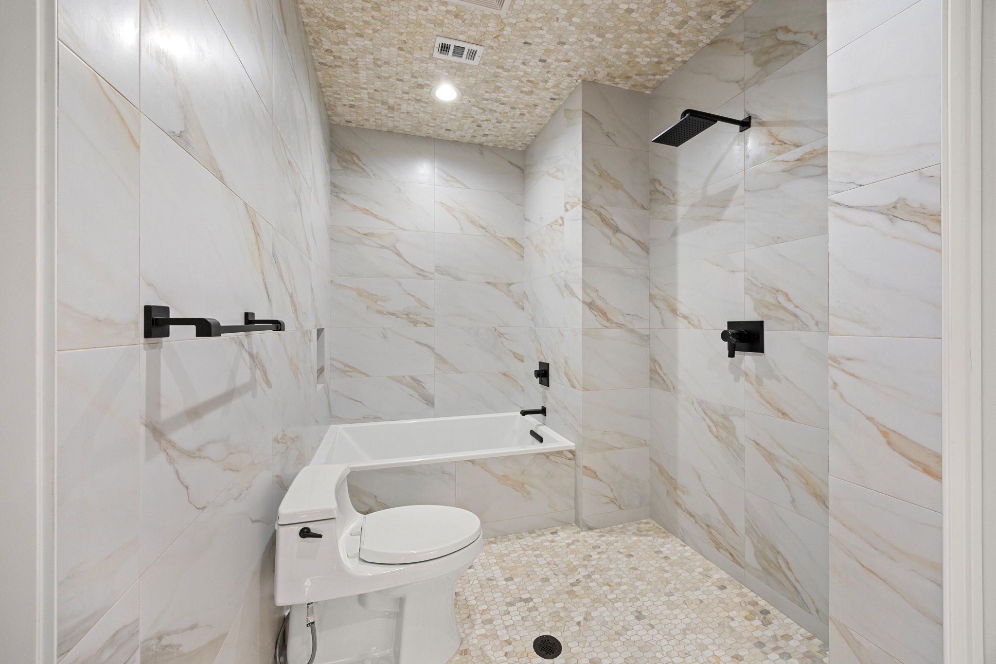 The downstairs primary bath features a modern wet room design, seamlessly integrating the shower, soaking tub, and toilet for a sleek, easy-to-maintain space.