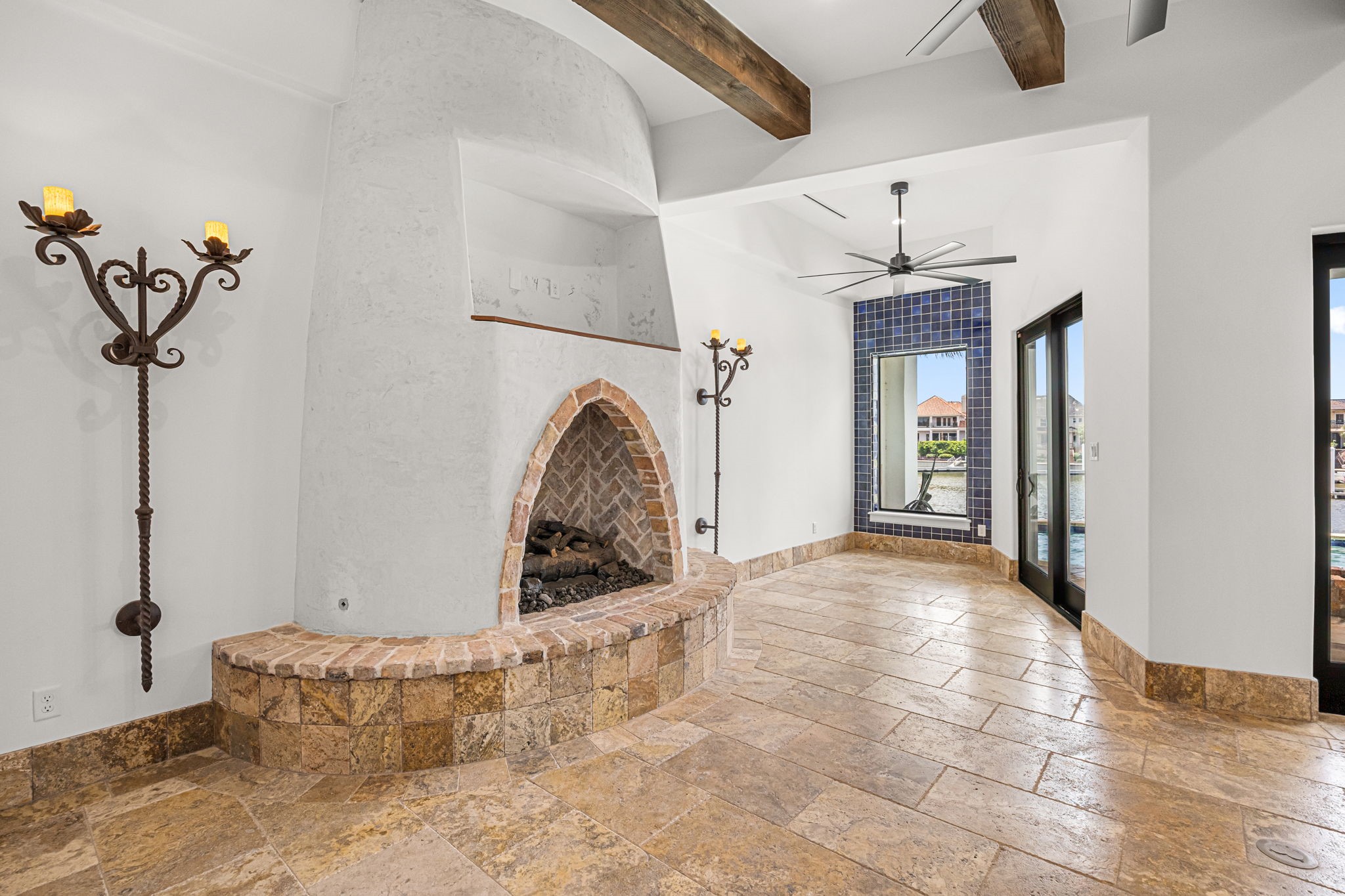 Rich travertine flooring flows throughout the living spaces, anchored by a custom-designed fireplace and complemented by views into the breakfast room, where Spanish tile accents add warmth and timeless Mediterranean charm. Rich travertine flooring flows throughout the living spaces, anchored by a custom-designed fireplace and complemented by views into the breakfast room, where Spanish tile accents add warmth and timeless Mediterranean charm.