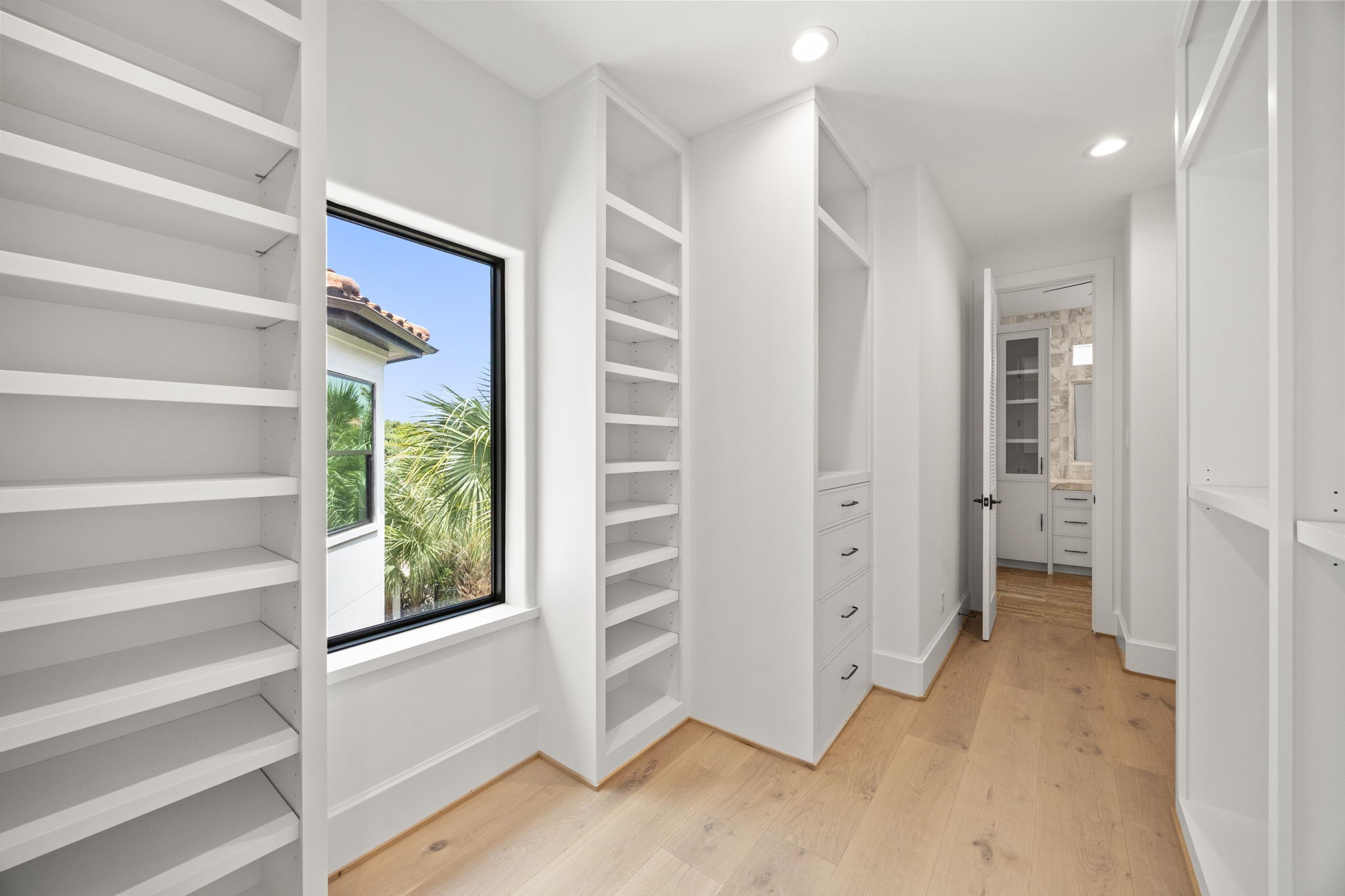 The upstairs primary closet offers abundant custom shelving and cabinetry, providing exceptional organization and storage.