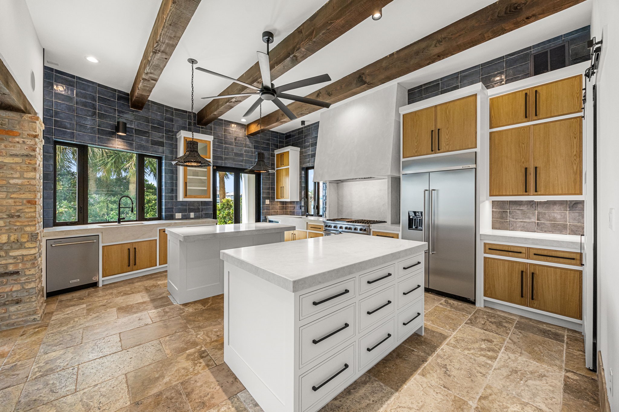 The chef's kitchen is a culinary masterpiece, anchored by a professional-grade Viking range featuring six burners, a griddle, and double ovens. Expansive double islands topped with marble countertops provide abundant prep and gathering space, while handcrafted Spanish tile accents add warmth and authentic Mediterranean character.