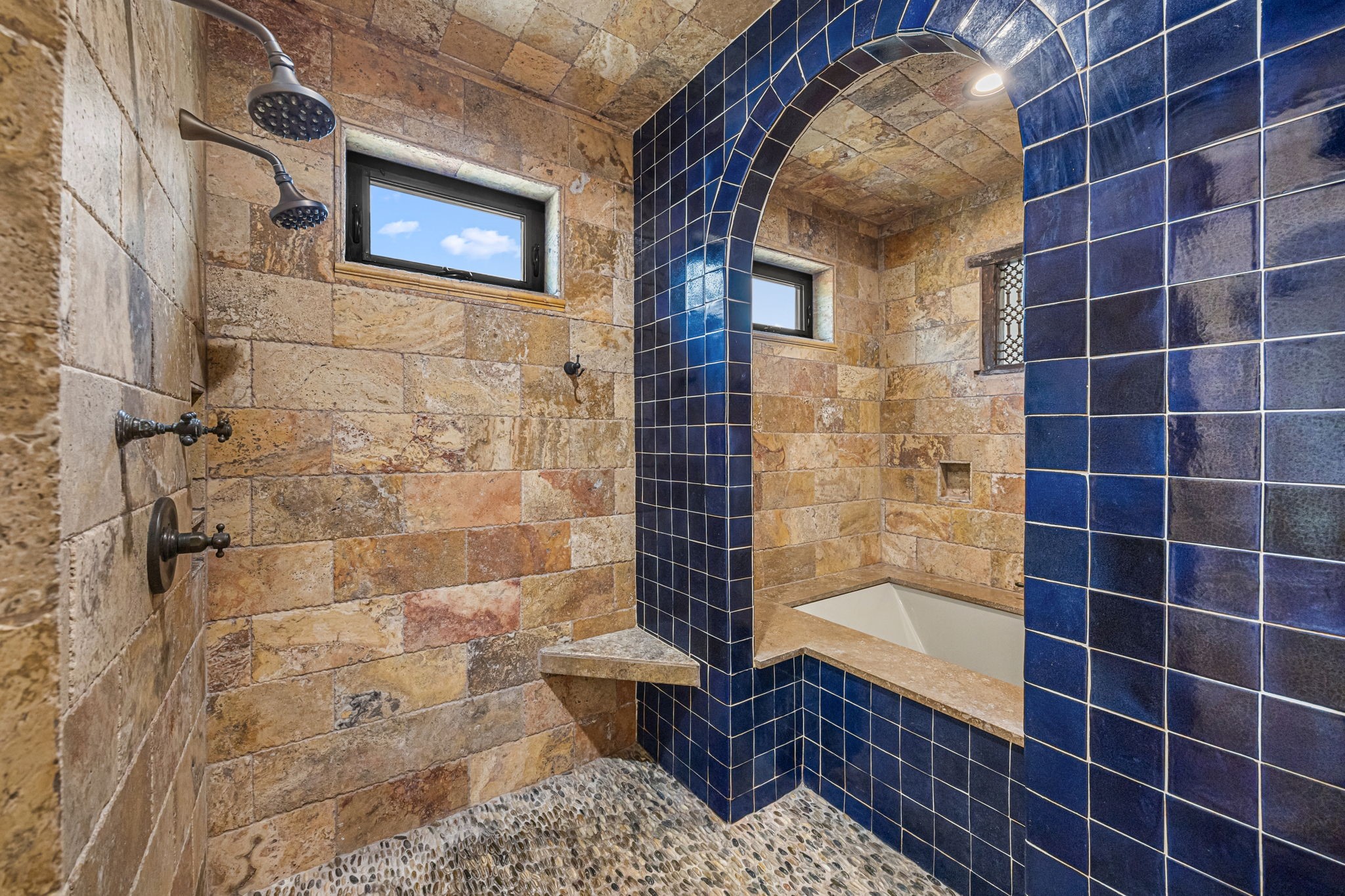 The upstairs primary bath features a spa-inspired wet area with three showers, complemented by travertine and Spanish tile finishes, and a separate soaking tub for ultimate relaxation.
