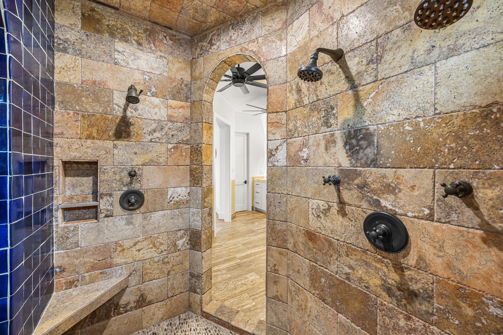 The upstairs primary bath features a spa-inspired wet area with three showers, complemented by travertine and Spanish tile finishes, and a separate soaking tub for ultimate relaxation.