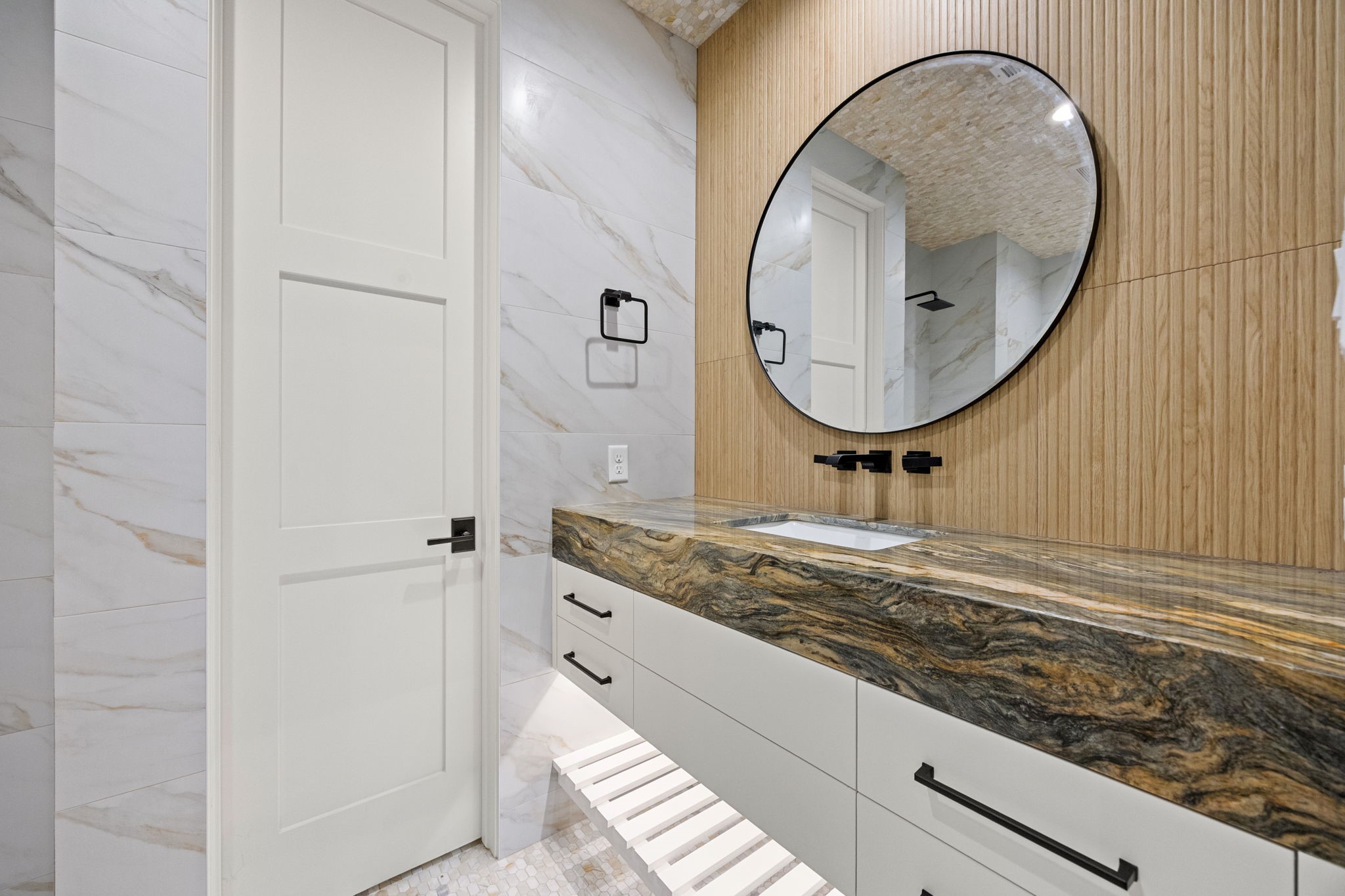 The downstairs primary bath features elegant floating countertops, creating a sleek, modern design with a light and airy feel.