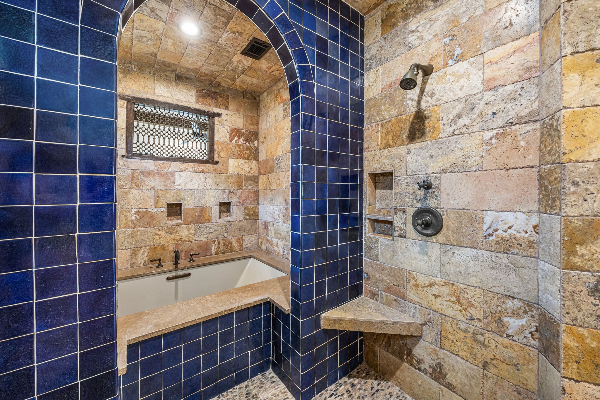 The upstairs primary bath features a spa-inspired wet area with three showers, complemented by travertine and Spanish tile finishes, and a separate soaking tub for ultimate relaxation.