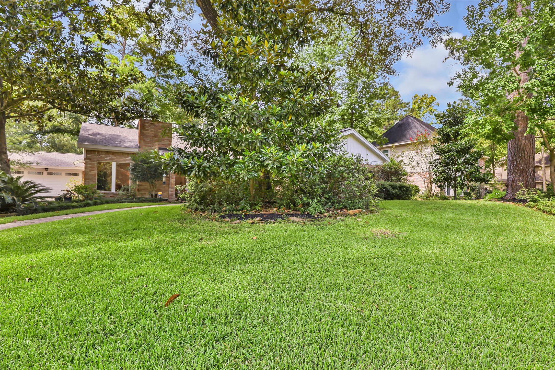 Expansive, lush green lawn surrounded by mature trees offers a serene and private setting for this charming home.