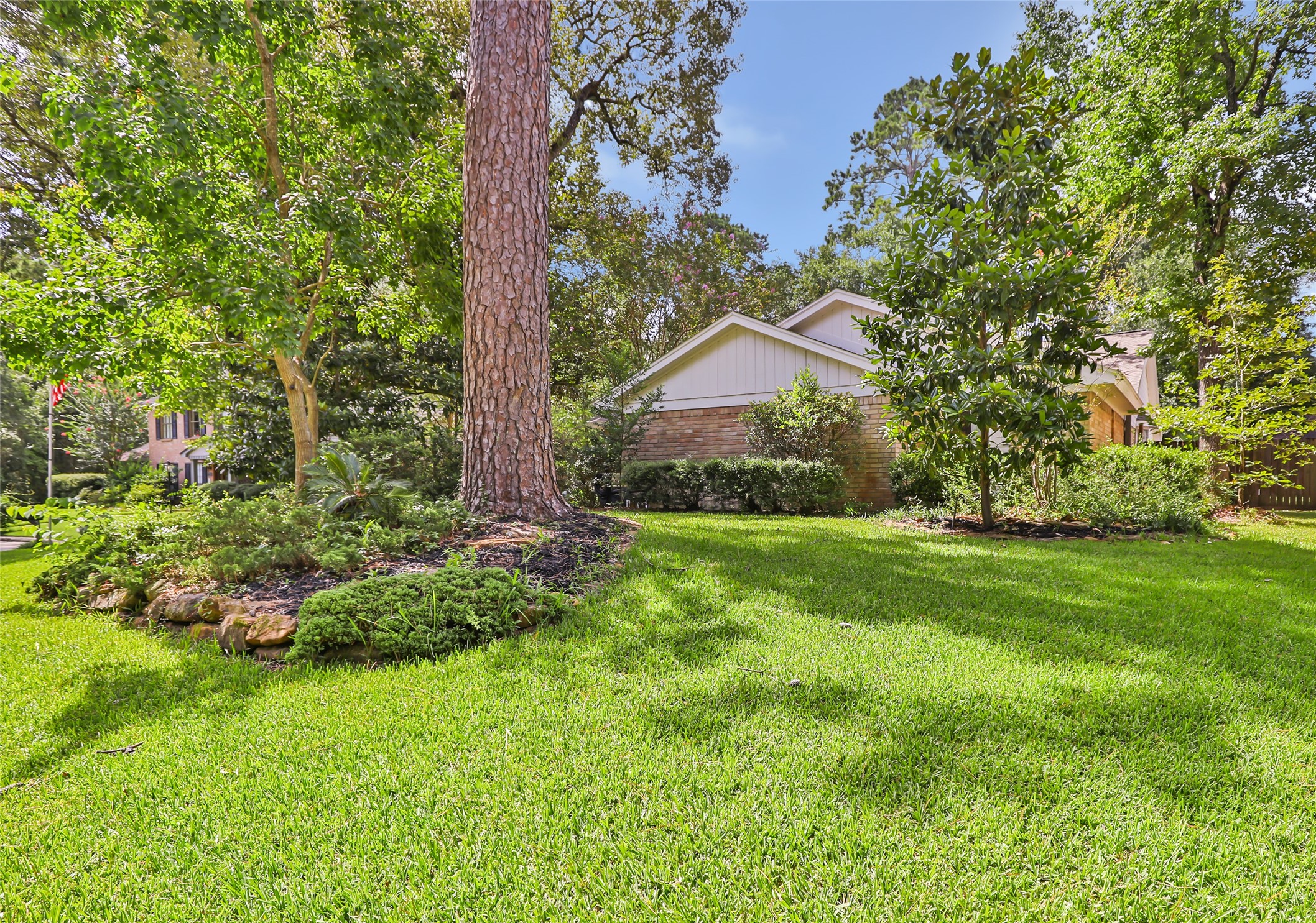 Expansive green lawn framed by mature trees and lush landscaping offers a serene, private setting for this charming home.