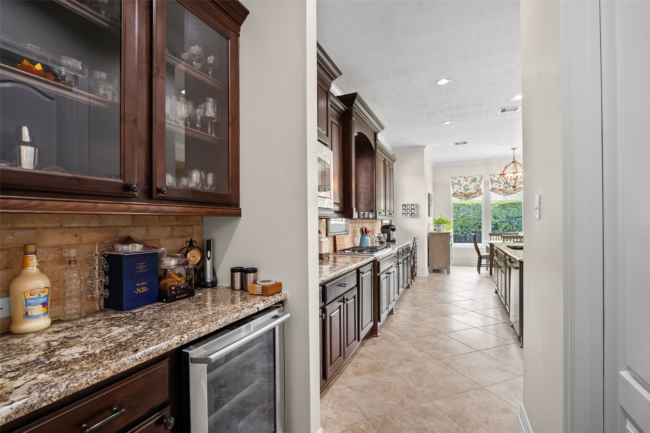 Butler pantry that includes a wine chiller past that is another view of the kitchen.  Large walk-in pantry is located to the right behind the door.  Look at all of the cabinets!  No shortage of storage space in this home.