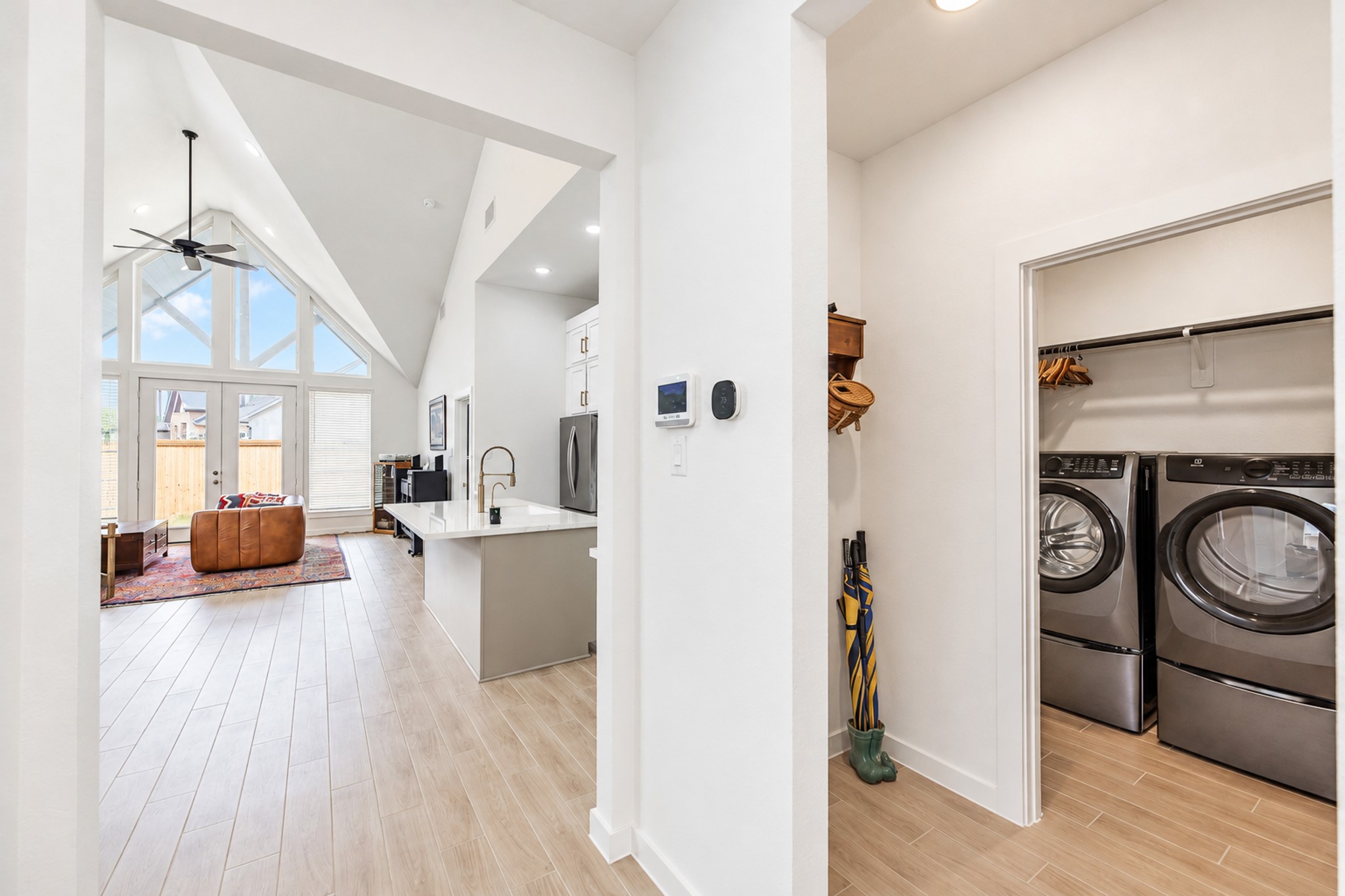Bright and open living space with soaring vaulted ceilings and large windows, complemented by a sleek kitchen and convenient adjacent laundry room.
