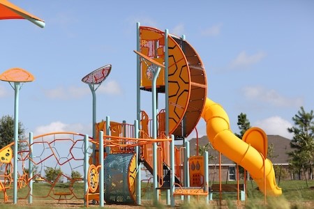 Vibrant playground featuring a climbing structure and a spiral slide, perfect for family fun and outdoor activities.
